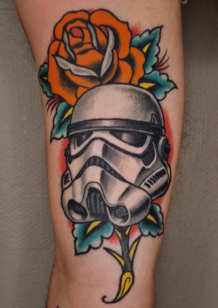 Tattoo of a Stormtrooper helmet from Star Wars surrounded by colorful roses and leaves.