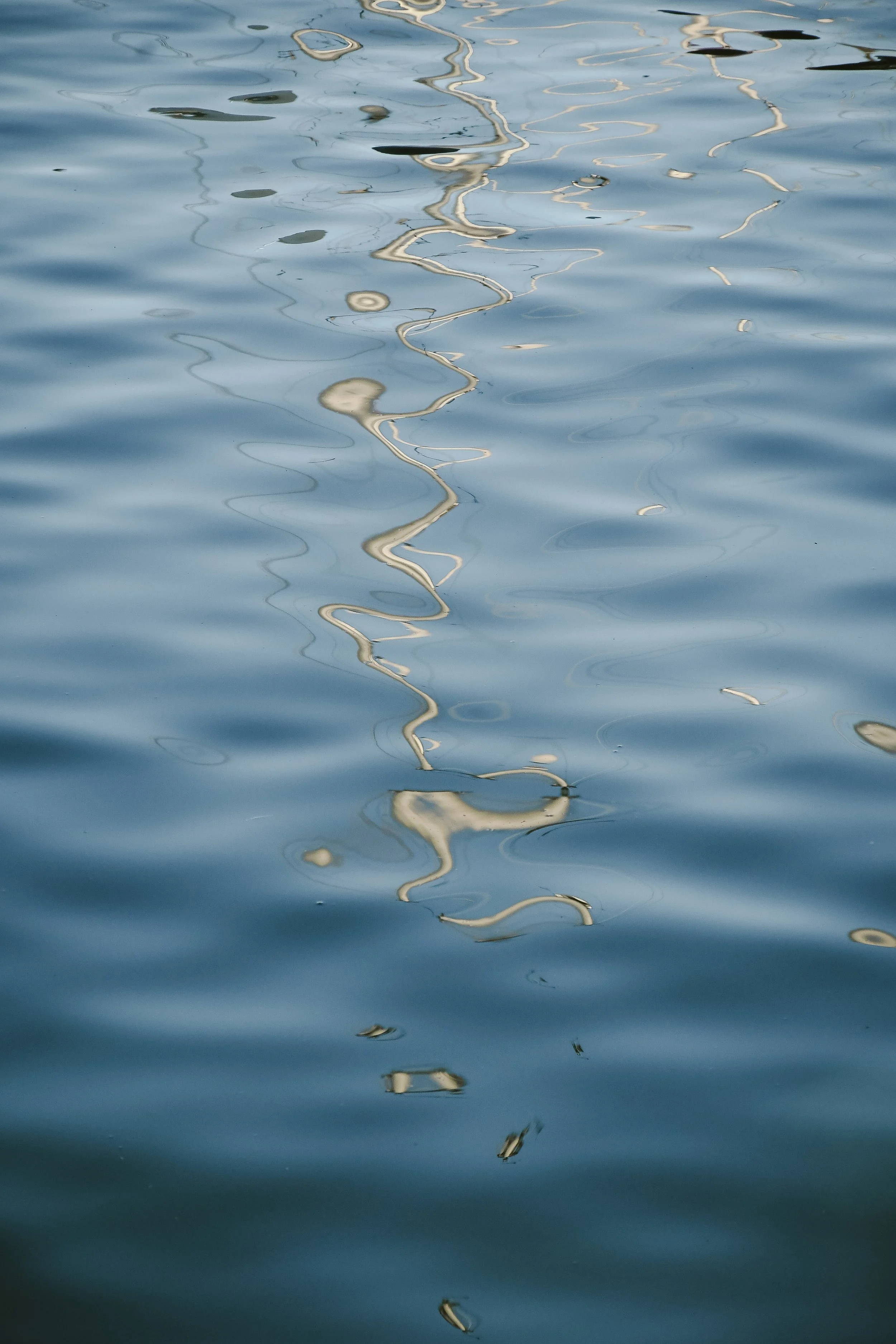 Reflet d'une corde ou d'une chaîne ondulant sur la surface calme de l'eau.