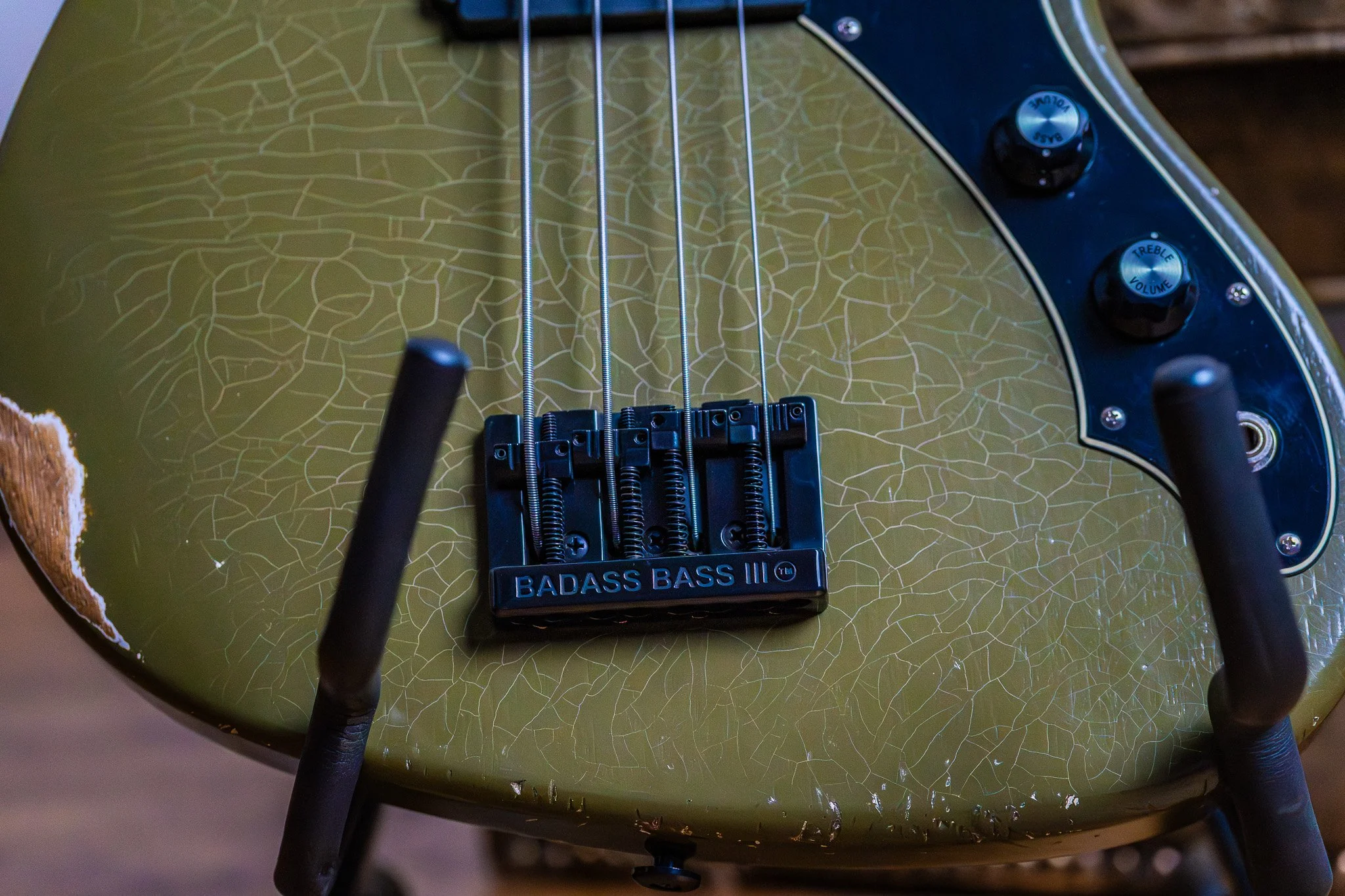 Een close-up van een groene elektrische basgitaar met een zachte crackle-afwerking en controleknoppen voor bas, treble en volume.