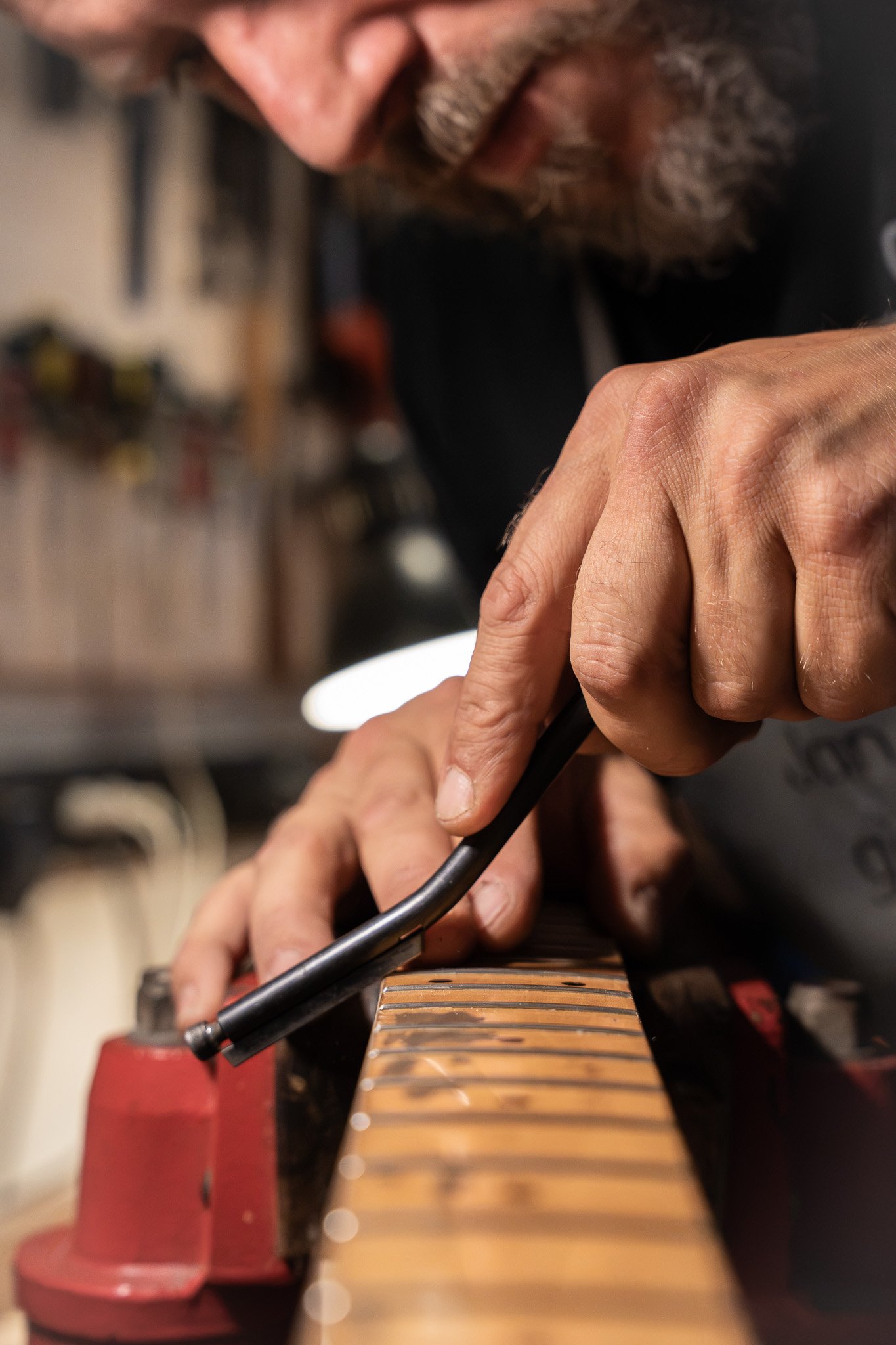Hand die een fretboard van een gitaar stemt met behulp van een stemapparaat, met vinger die een snarenknipper vasthoudt.