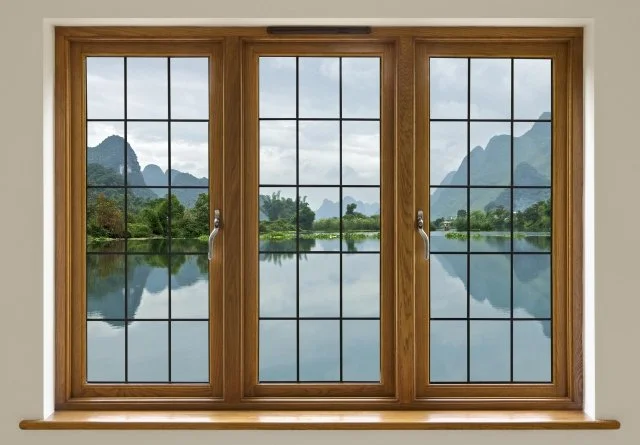 Wooden framed glass sliding doors showing a scenic view of a lake with mountains and a cloudy sky.