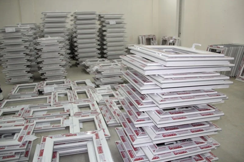 Various window frames and sashes stacked neatly in a warehouse or storage room.