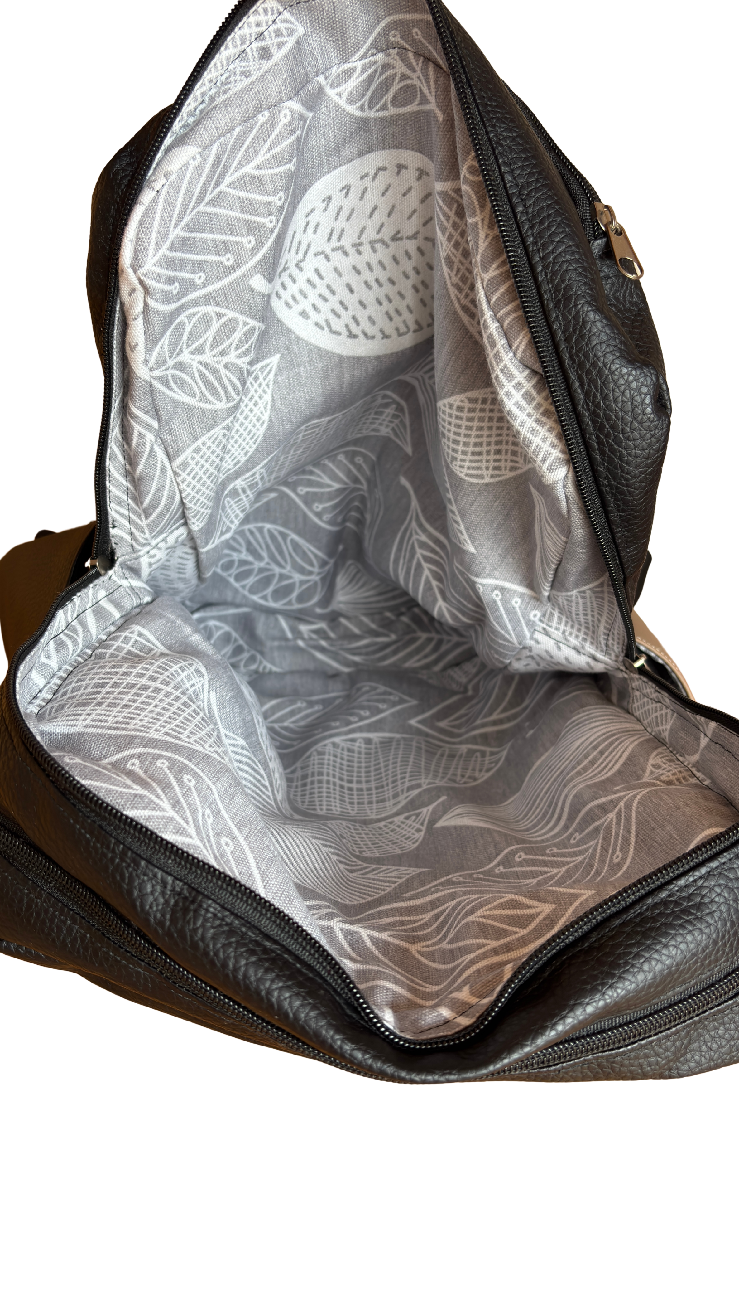 Leerer, schwarzer Rucksack mit durchsichtigem Innenfutter mit weißem Blattmuster, geöffnet.