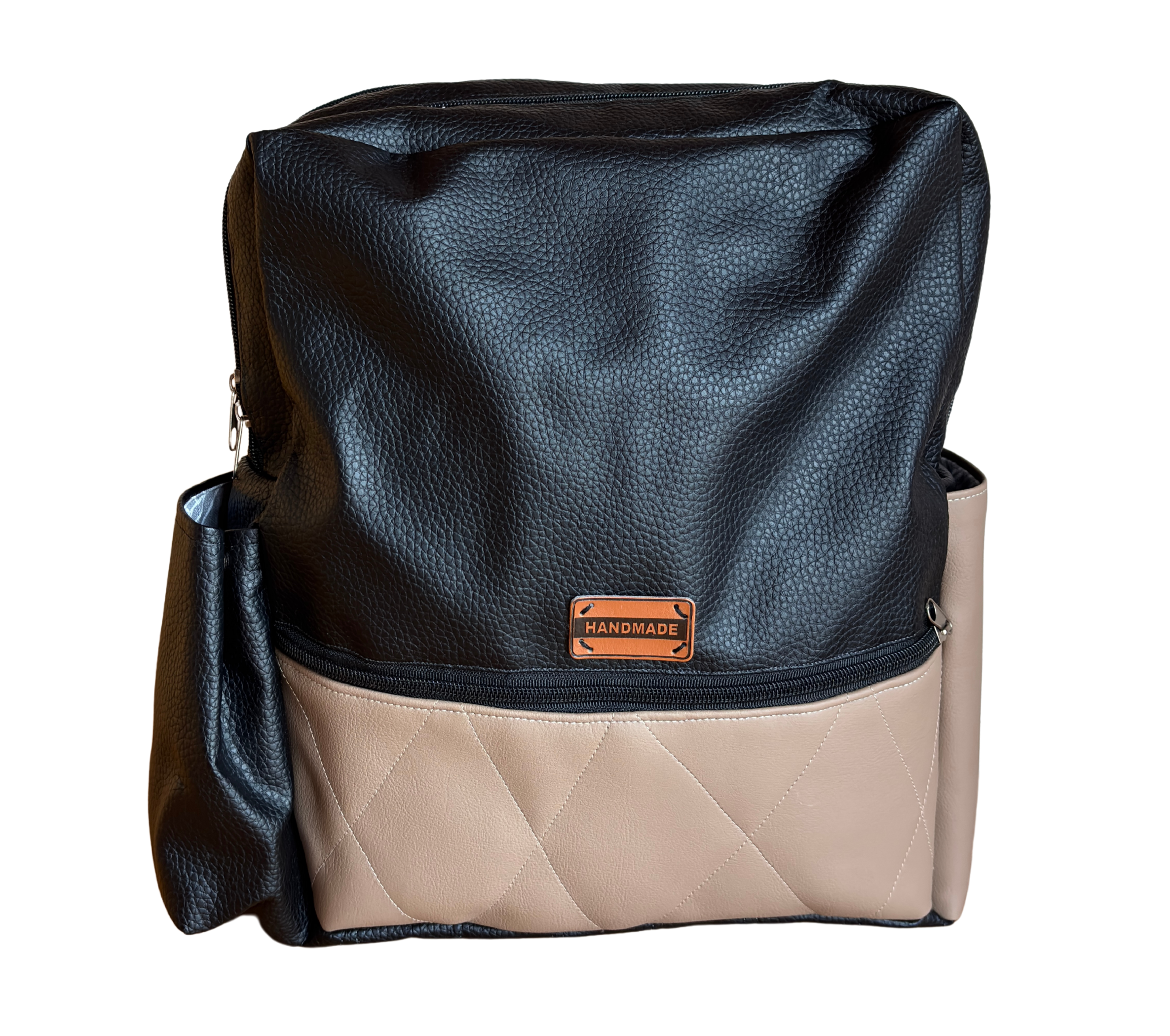 Ein Rucksack aus schwarzem und beigem Kunstleder mit einem braunen Handmade-Label.