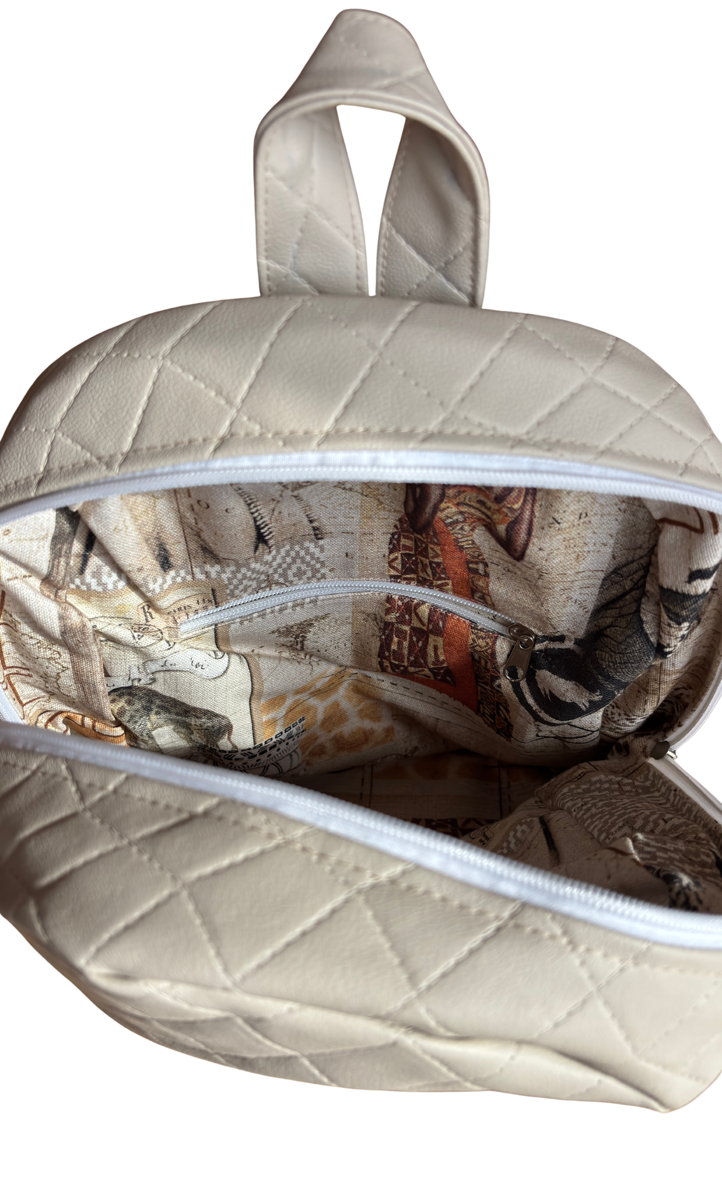 Aufgeklappte, cremefarbene Tasche mit Innenfächern und Reißverschlüssen, das Innenfutter zeigt ein grafisches Muster mit Tieren und Text.