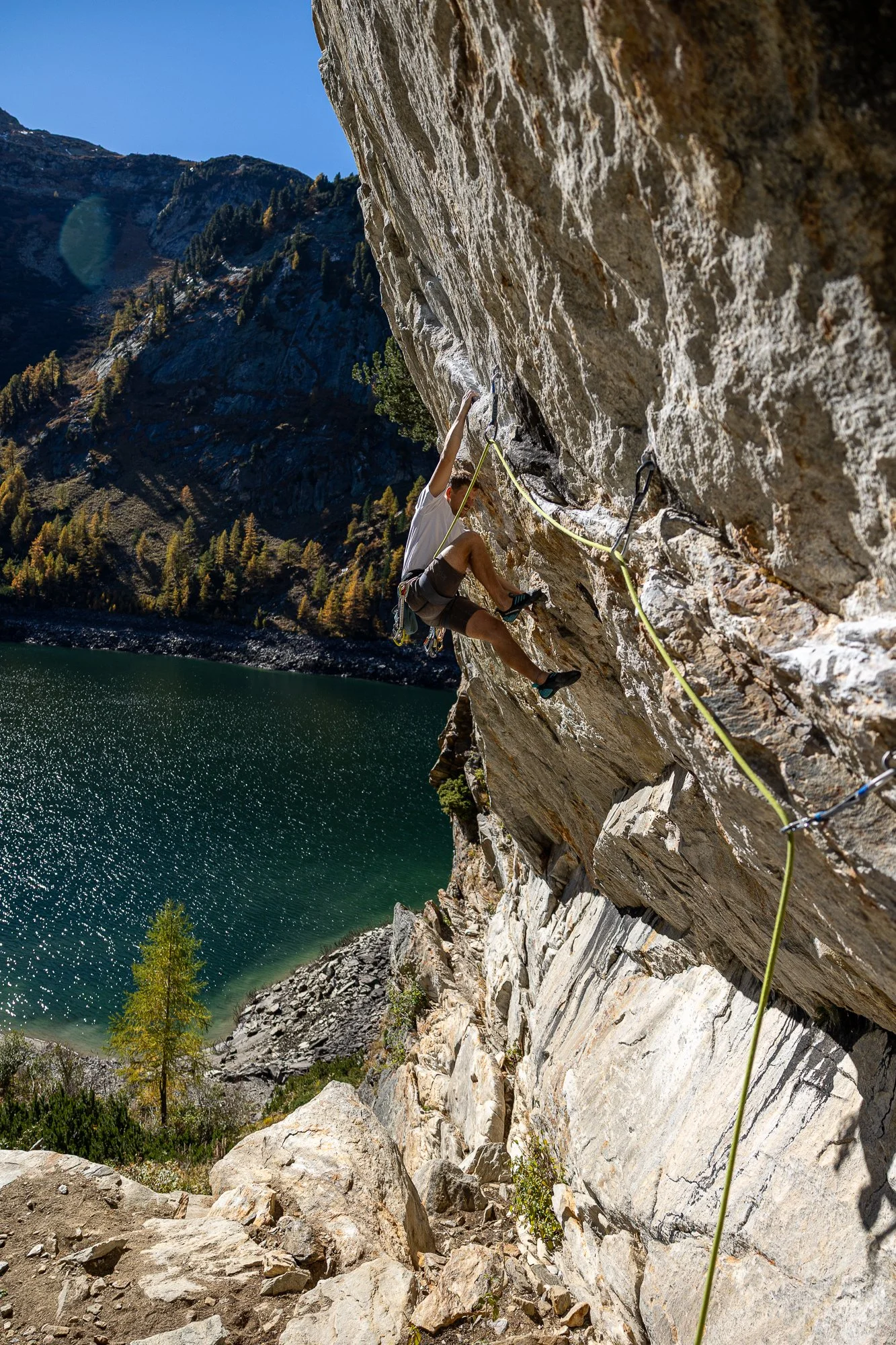 Kletterer an einer Felswand über einem See in den Bergen.