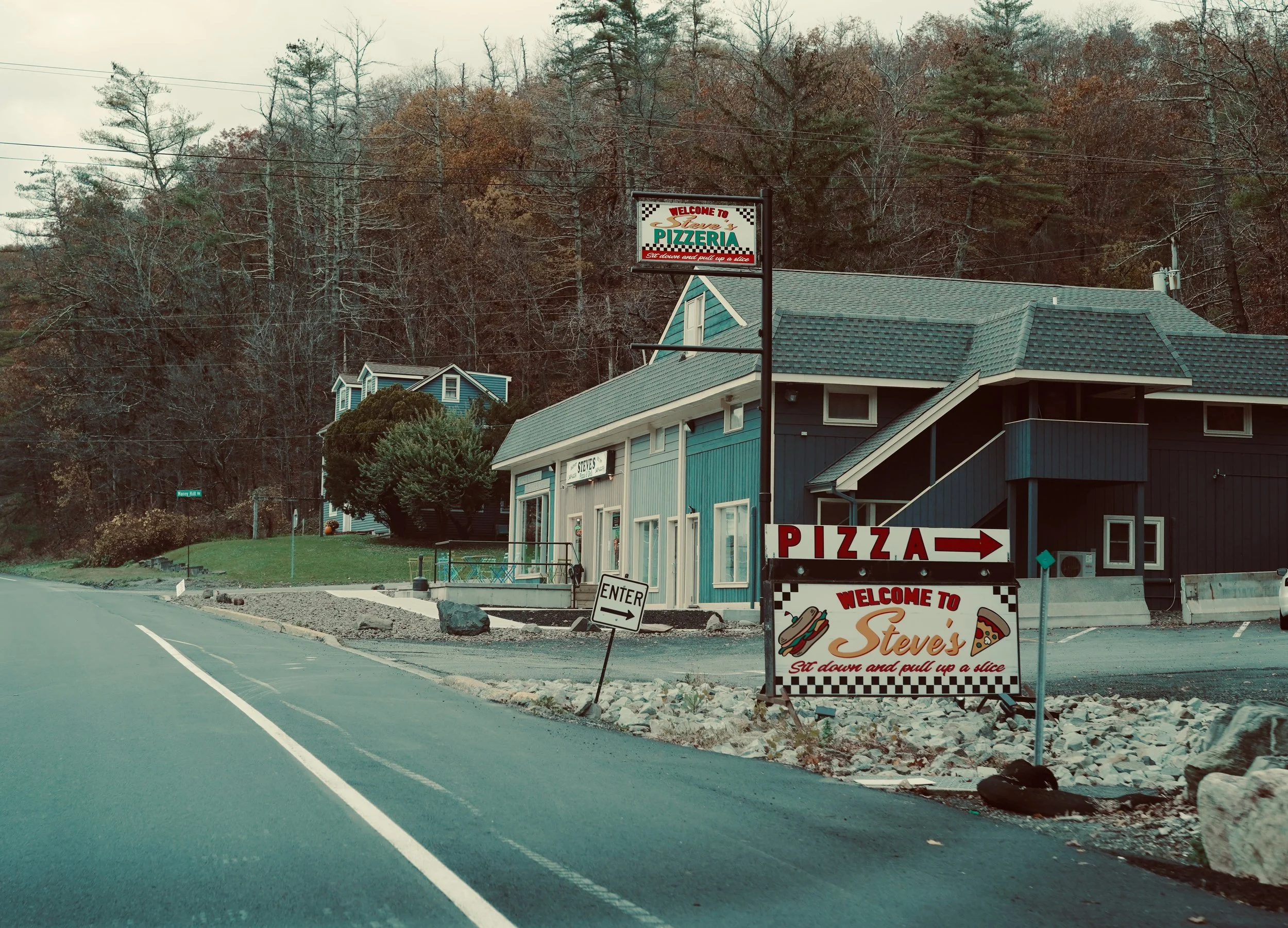 Small storefront with signs indicating a pizzeria named Steve's, with a 