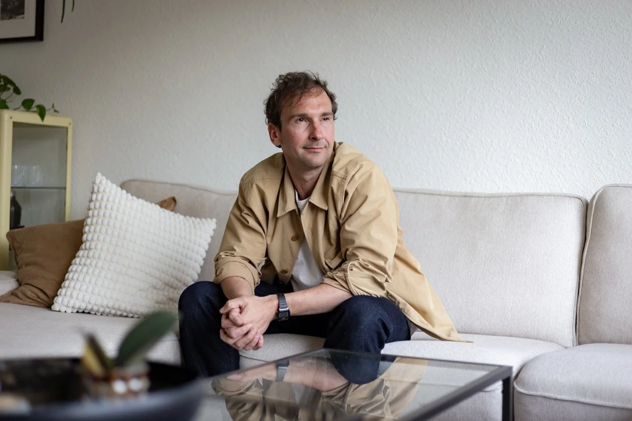 Thomas Ploch auf einem Sofa sitzend und in die Ferne schauend