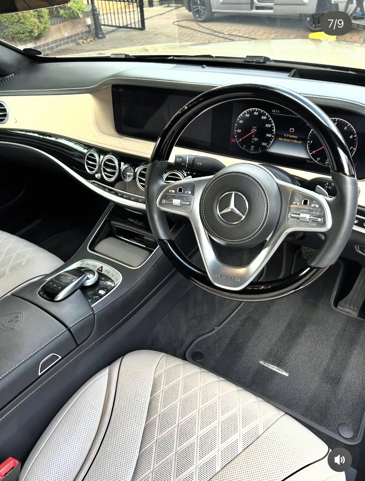 Interior of a Mercedes-Benz car showing the steering wheel, dashboard, and center console with control pad, gear, and digital display.