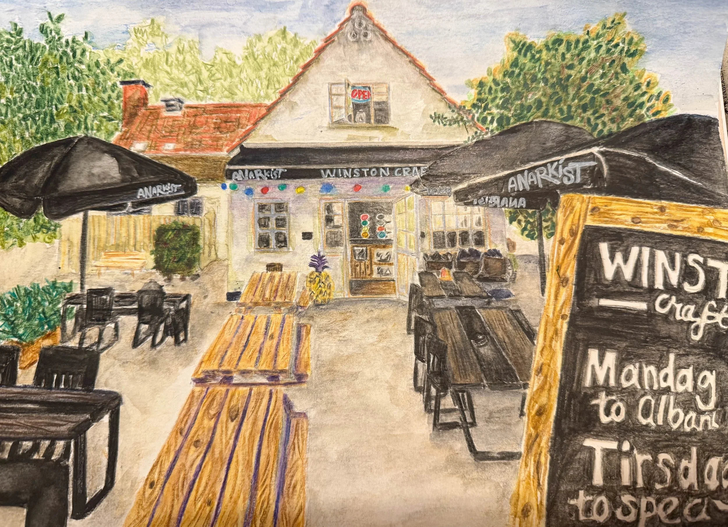 A watercolor painting of a cozy outdoor café with black umbrellas labeled "Anarkist" and a sign with menu items, with a building in the background featuring a window with an "Open" sign and trees on either side.