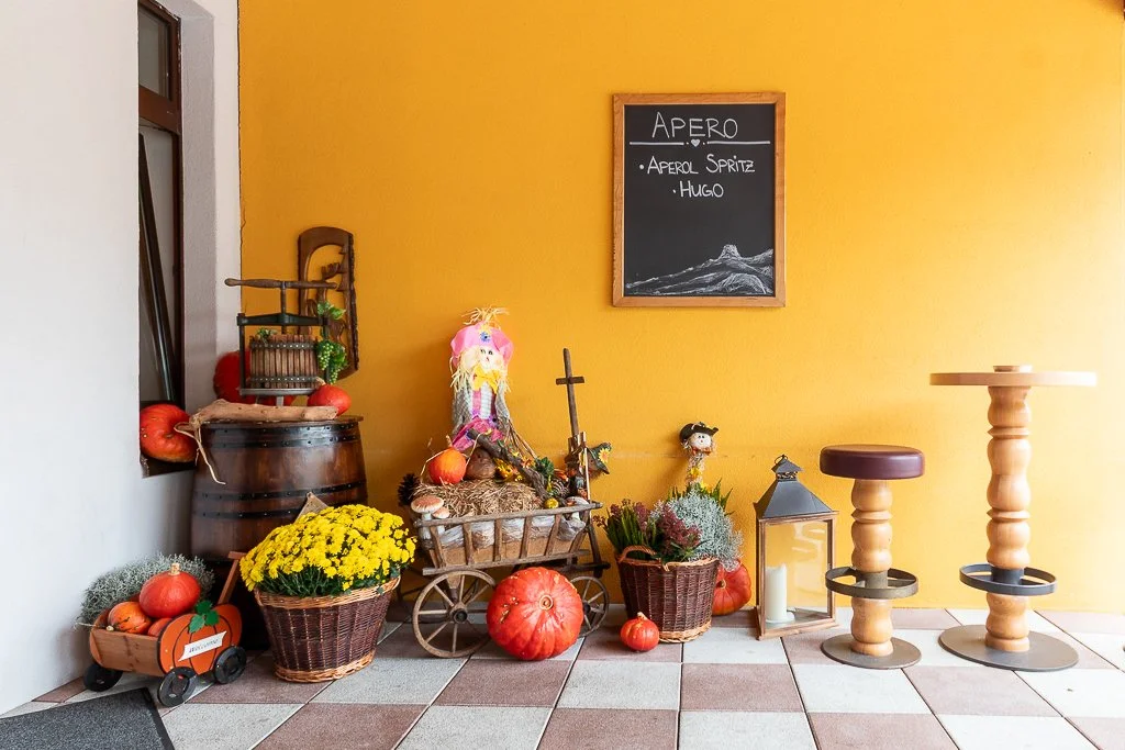Herbstdekoration mit Kürbissen, Blumen, Laterne und dekorativen Figuren vor einem gelben Wand