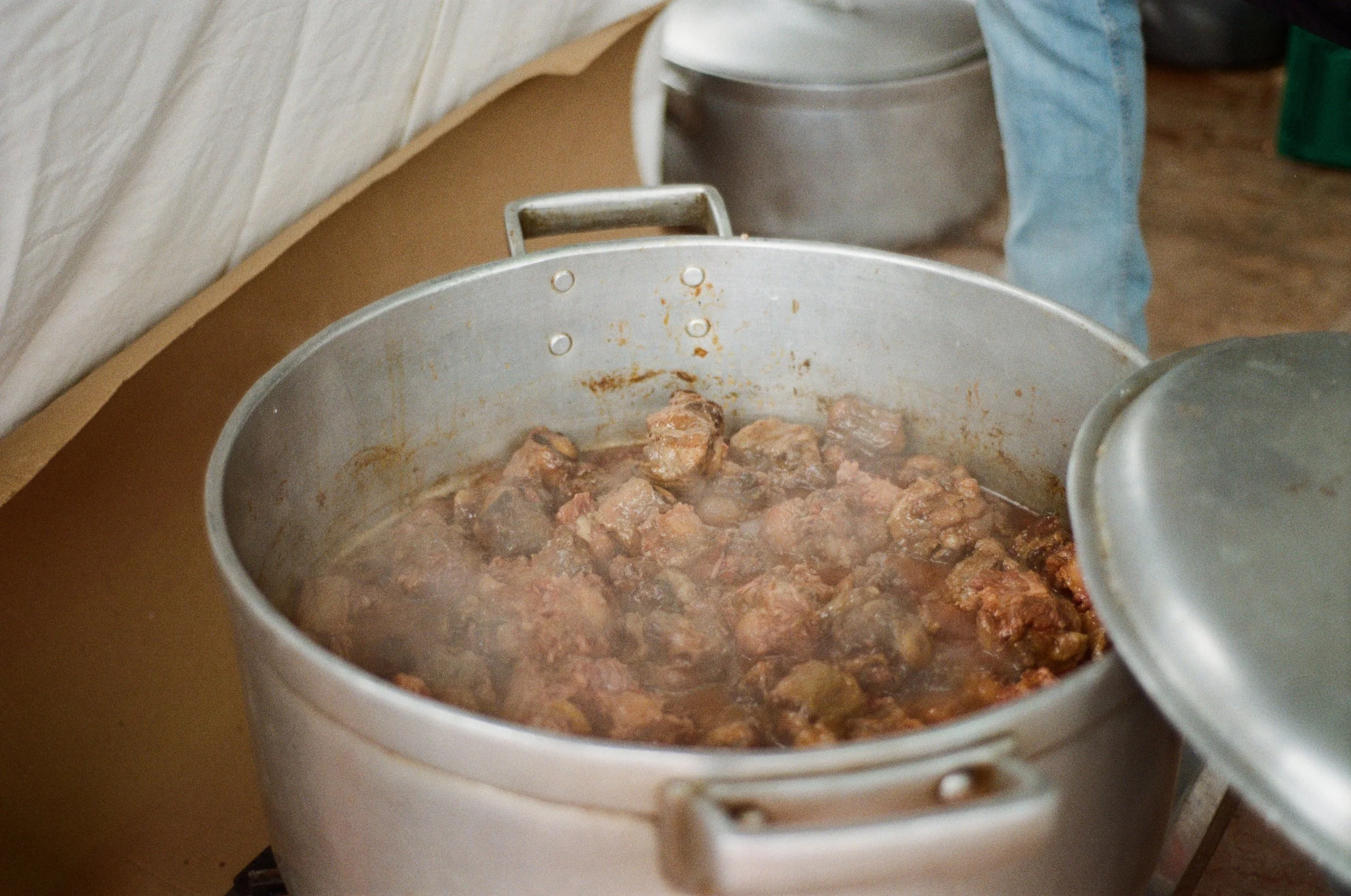 Panelas com carne cozida em fogo, com vapor saindo, em cozinha.