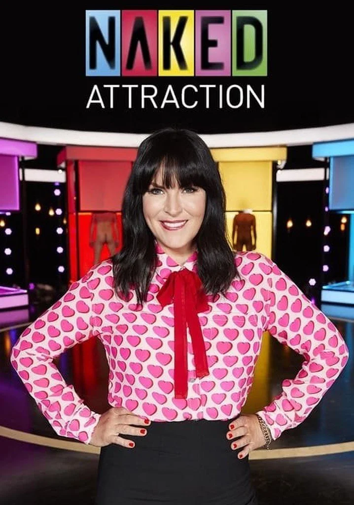 A woman standing in front of a colorful game show set with the words 'NAKED ATTRACTION' displayed. She is wearing a pink blouse with red heart patterns and a red bow tie, smiling and posing with her hands on her hips.