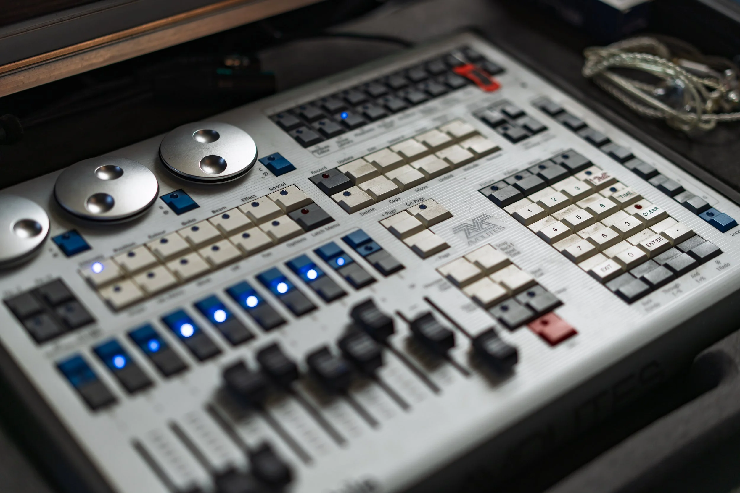 Close-up of a vintage electronic music synthesizer with numerous buttons, knobs, and LED indicators, on a wooden surface.