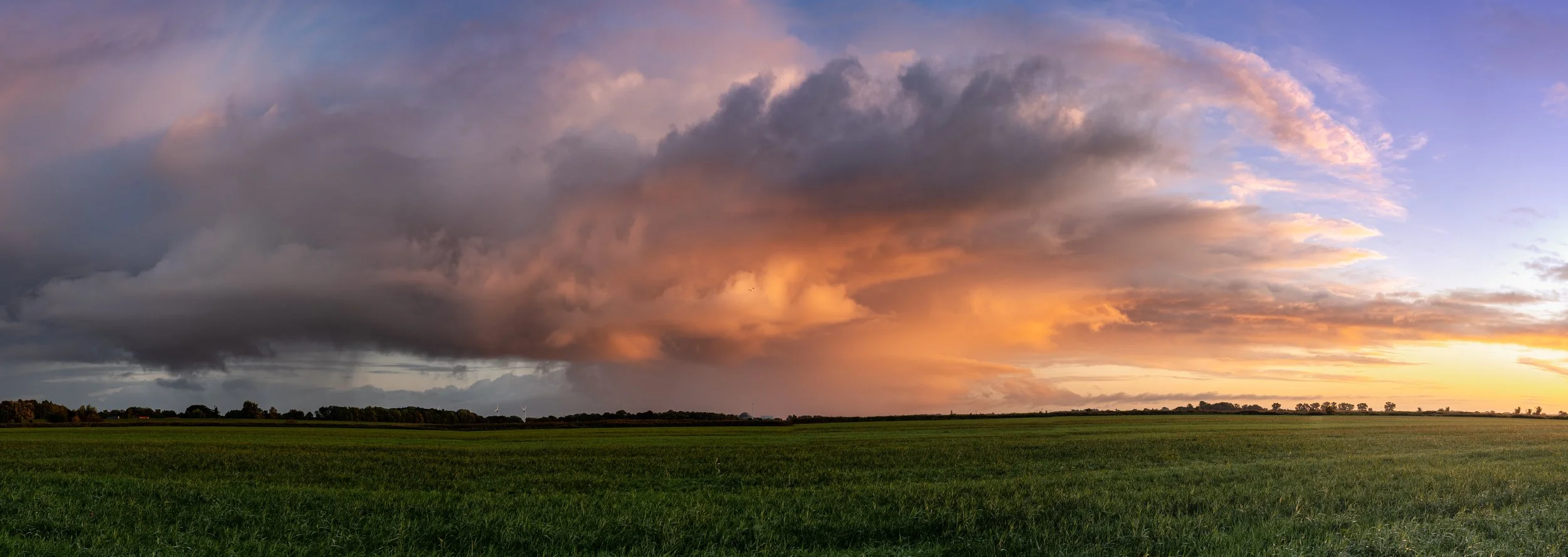Eine große Regenwolke wird von der Morgensonne angeleuchtet