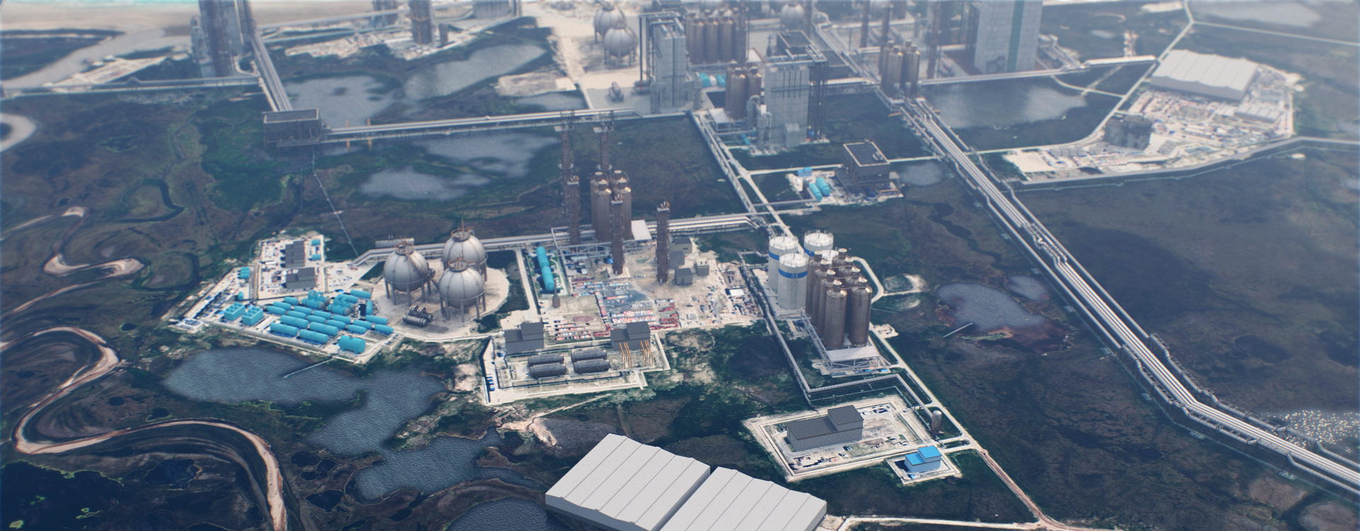 Aerial view of a large industrial complex with multiple buildings, storage tanks, cooling towers, pipelines, and water bodies surrounded by greenery and roads.