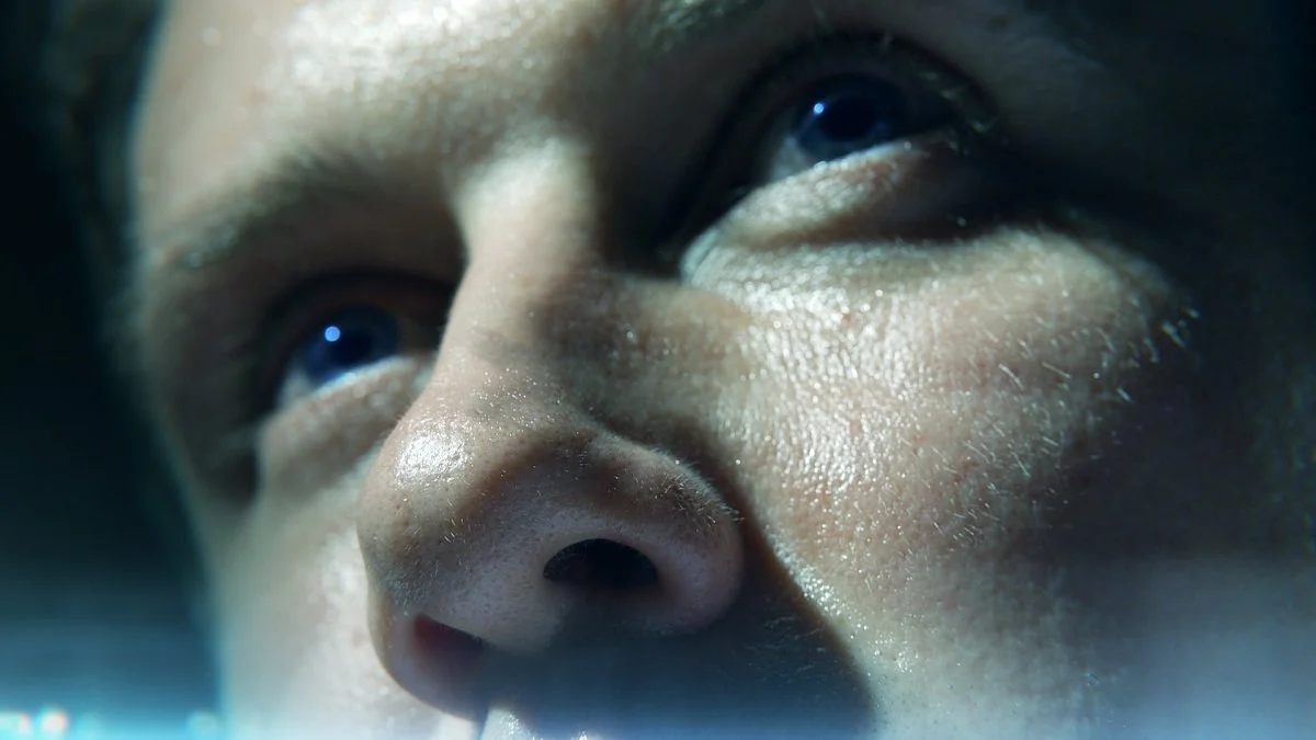 Close-up of a person's face showing their eyes and nose, with water or sweat on their skin.