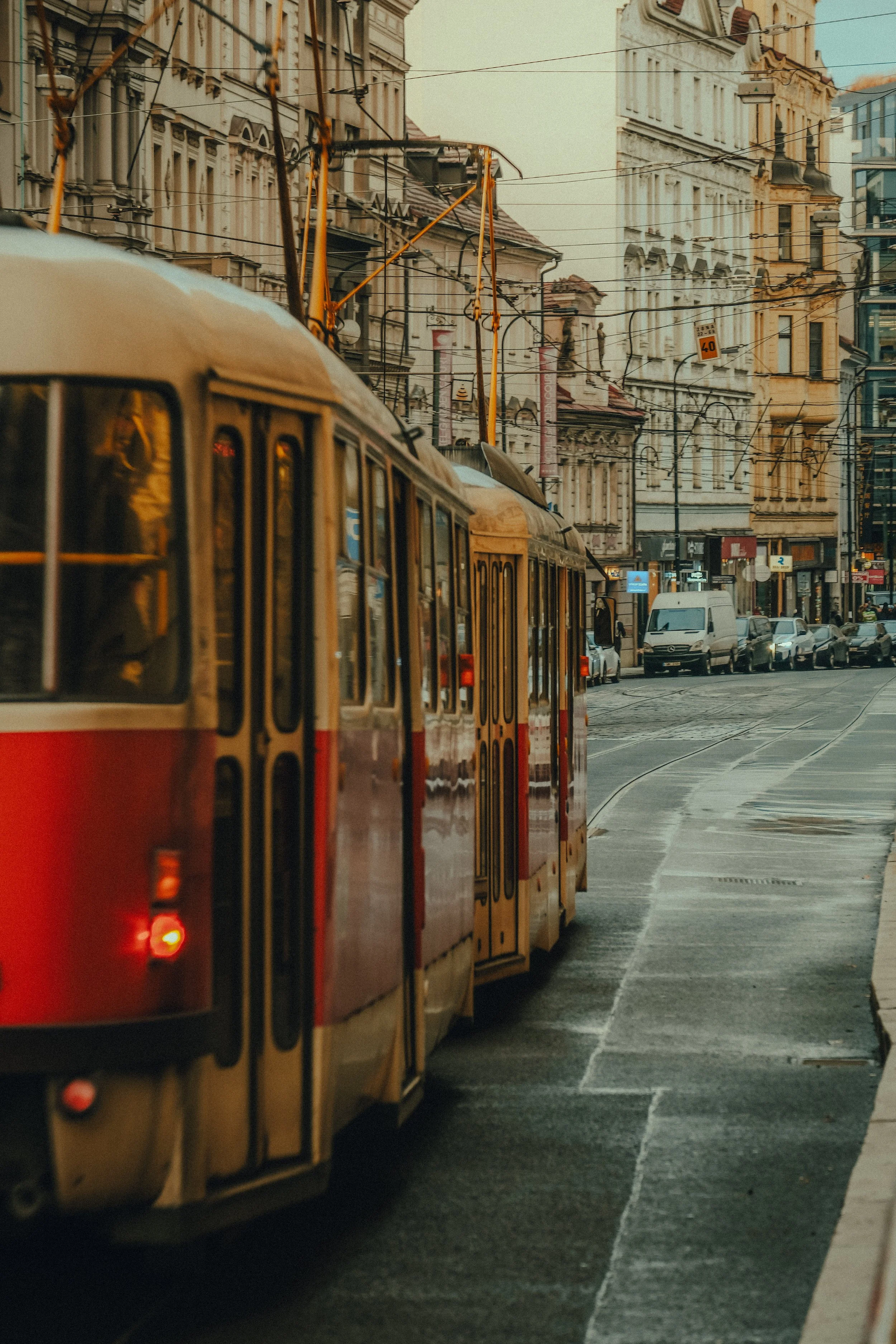 Straßenbahn fahre durch eine Stadt mit alten Gebäuden und mehreren parkenden Autos.