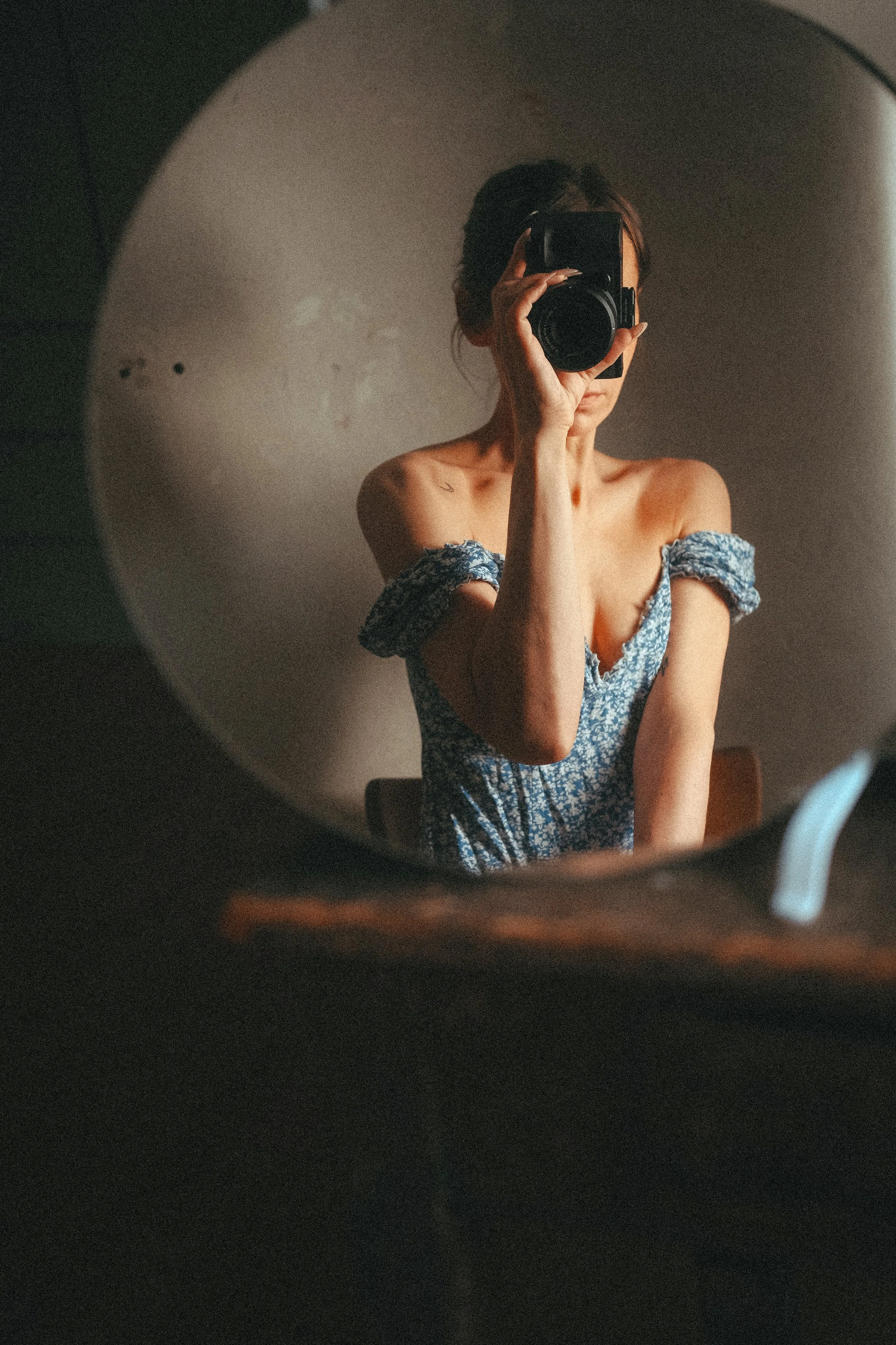 Frau in blauem Kleid, nimmt Selfie mit Kamera in einem runden Spiegel auf