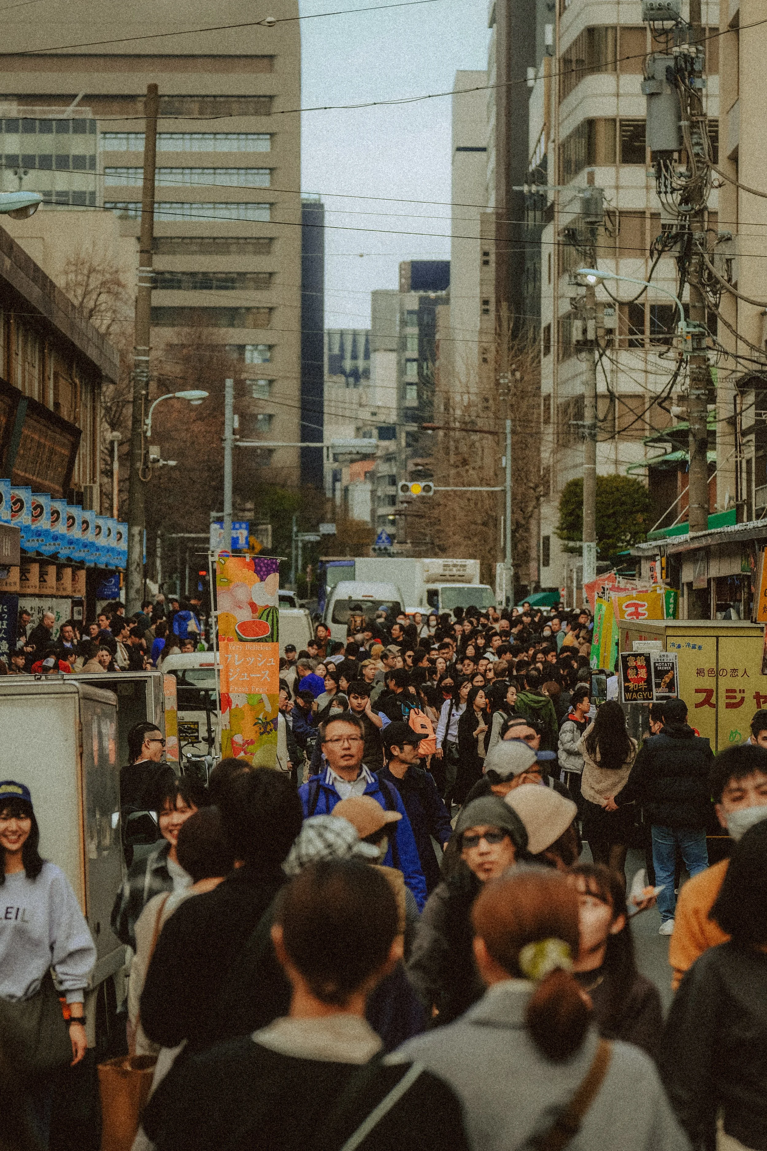 Ein belebter Stadtstraßenabschnitt mit vielen Menschen, Geschäften und hohen Bürogebäuden, typisch für eine geschäftige Stadt.
