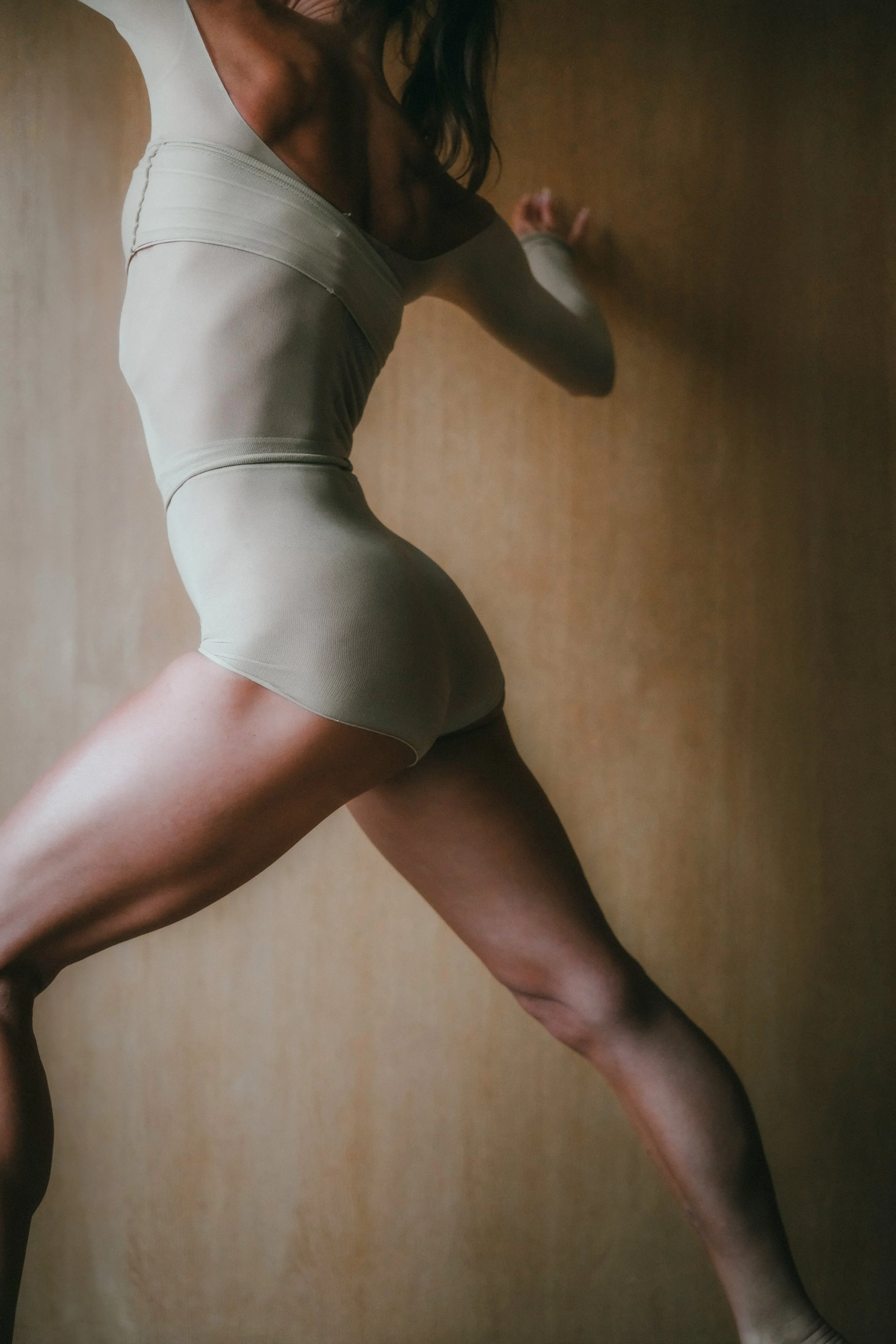 Nahaufnahme einer Frau in beiger Kleidung, die gegen eine Wand drückt.