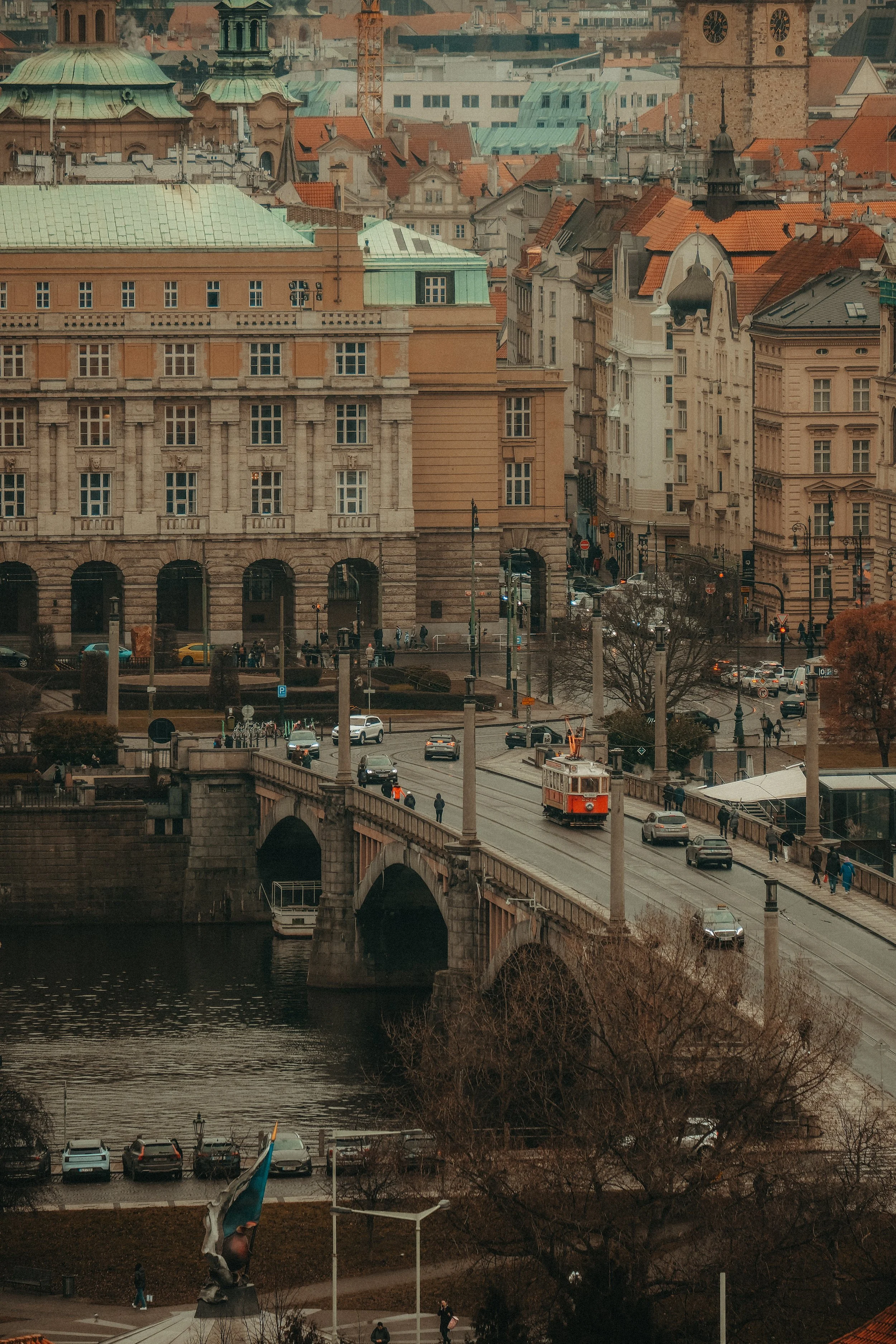 Stadtansicht mit Brücke, Straßenbahn, Autos und historischen Gebäuden in Prag im Herbst.