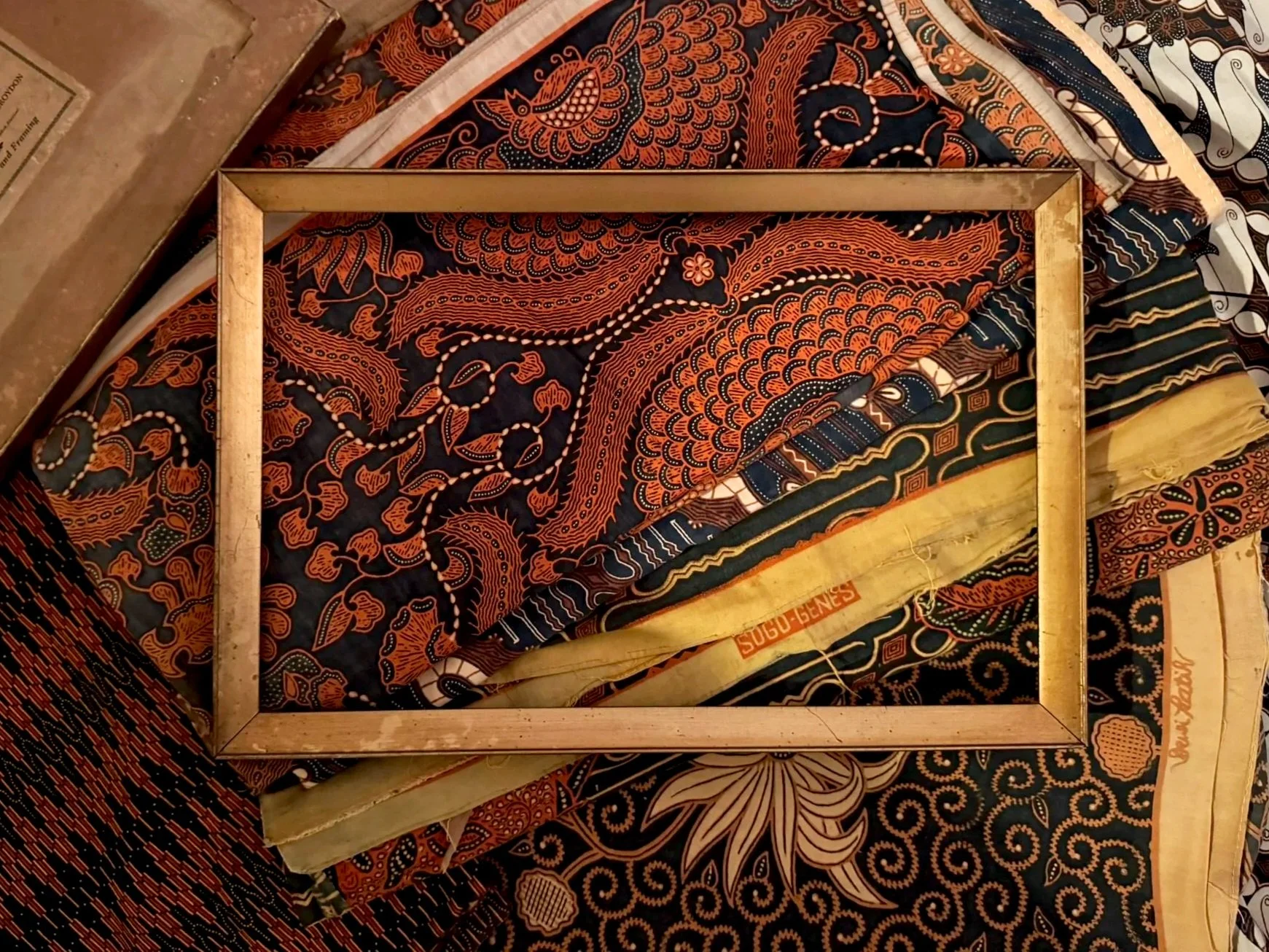 Colorful fabric with intricate traditional Asian patterns and a wooden frame on top.