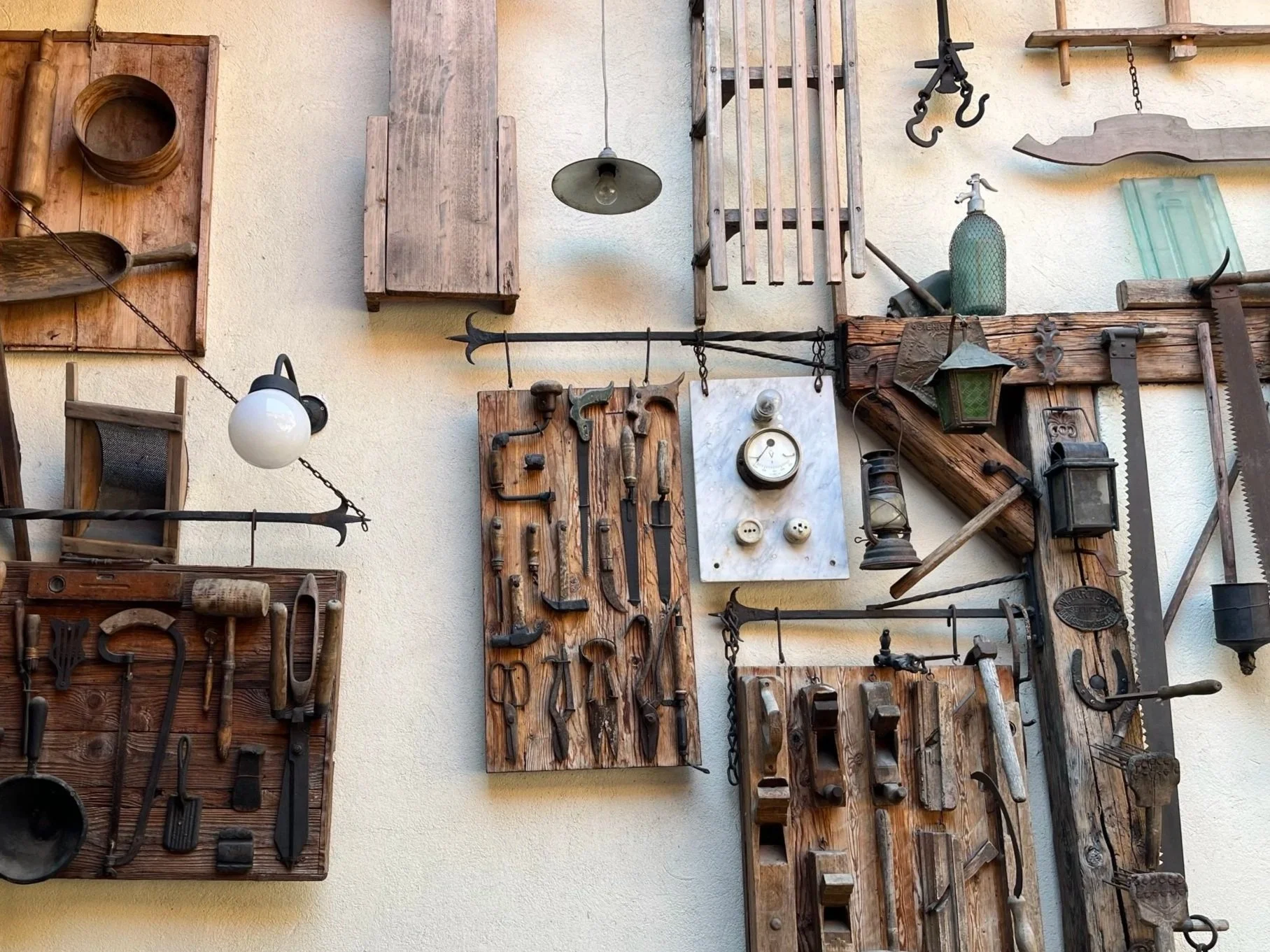 Wall decorated with vintage tools, lanterns, and wooden panels.