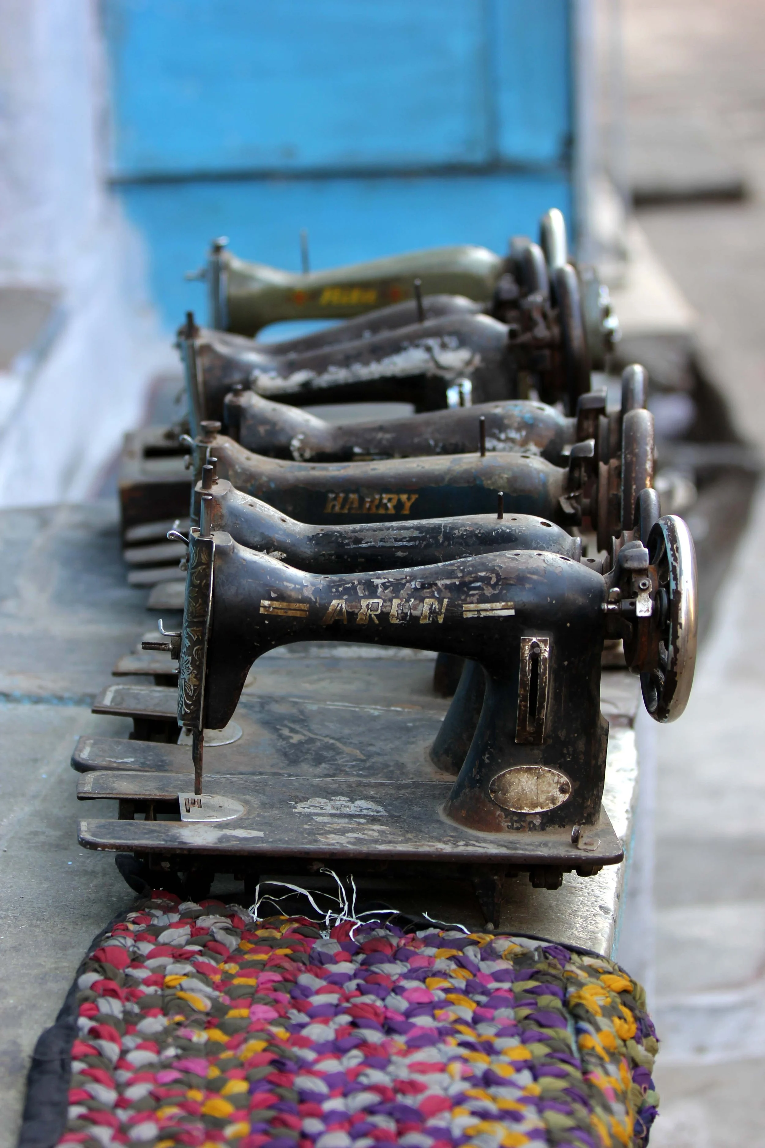 Several vintage black and green sewing machines lined up on a wooden surface.