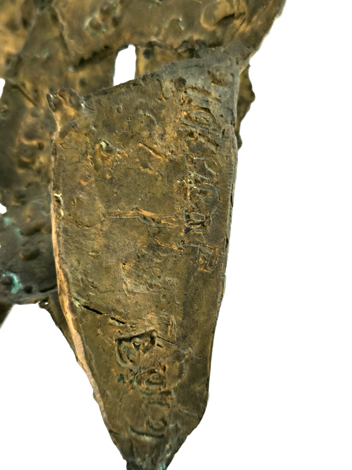 Close-up of a worn, old metal artifact with embossed and engraved markings, possibly a military or historical item.