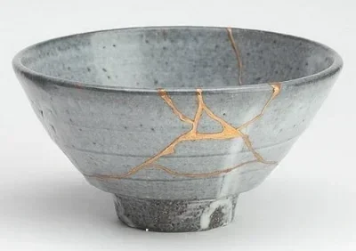 A cracked gray ceramic bowl with gold repair lines in the cracks.