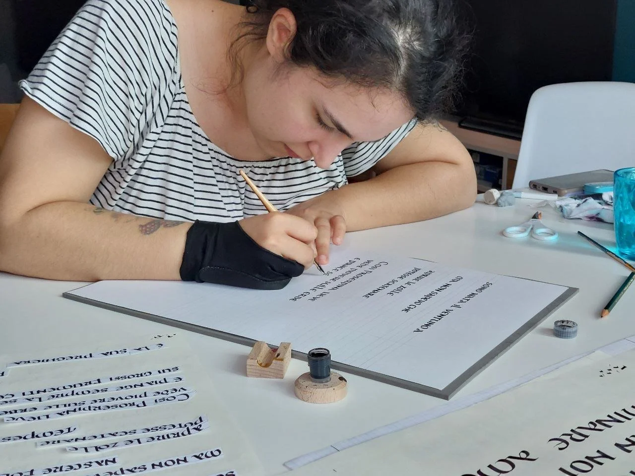 Una giovane donna scrive su una lavagna bianca con un pennarello, circondata da strumenti di scrittura e materiali artistici.