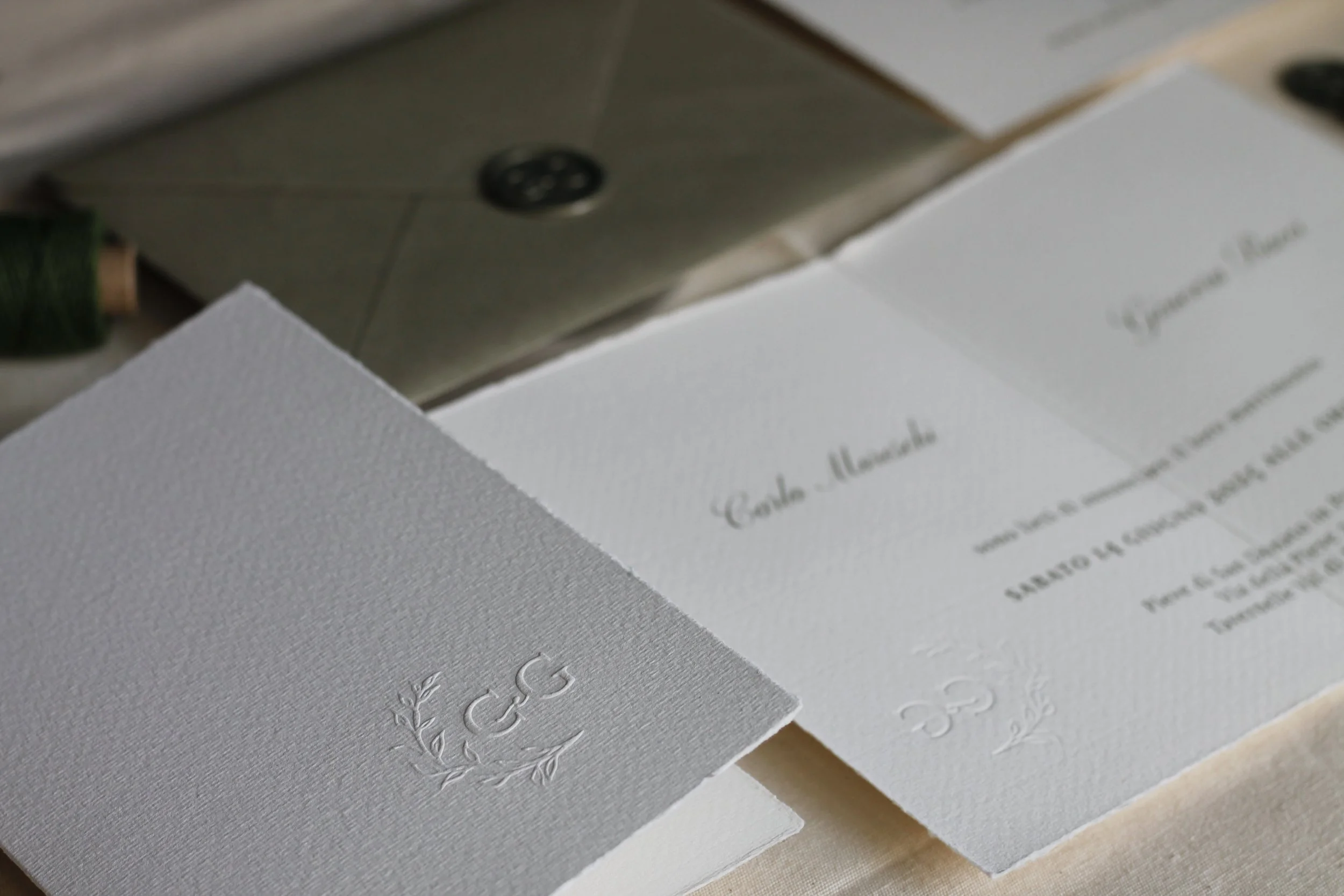 Invito di matrimonio bianco con incisione logo con lettere 'CG' e decorazioni floreali.