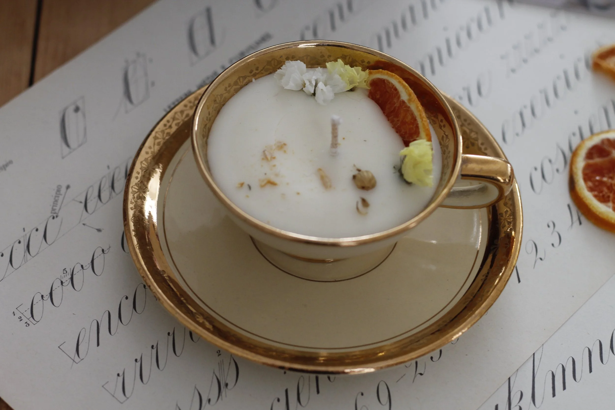 Candela decorativa in tazza con candele profumate e decorazioni di agrumi e fiori.