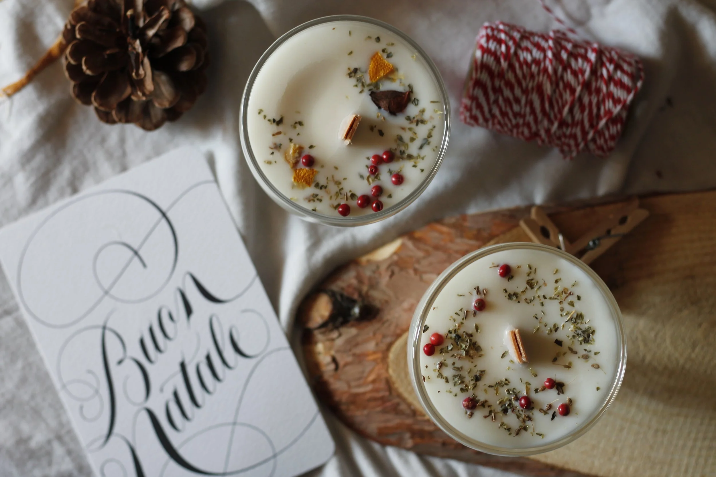 Candele di Natale decorati con spezie, bacche rosse e scorza di agrumi