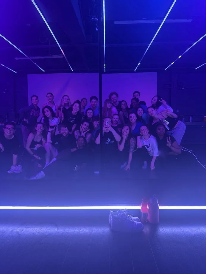 Dance Class in Nottingham of people taking a mirror selfie in a dimly lit, purple and blue neon-lit dance or fitness studio