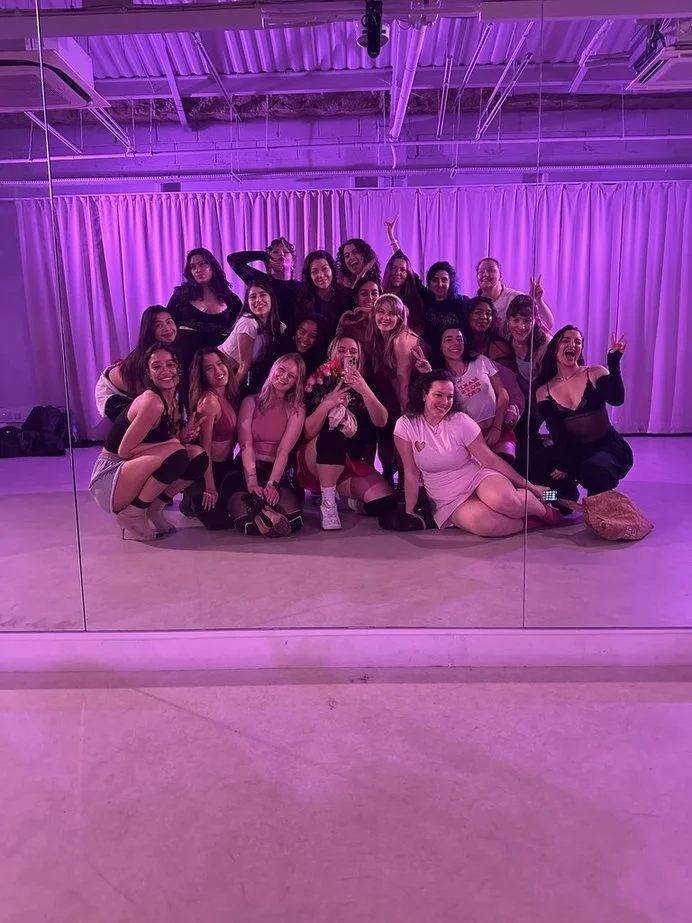 Group of women posing for a mirror selfie in a dance studio with purple lighting and curtains in the background after a dance class in Nottingham