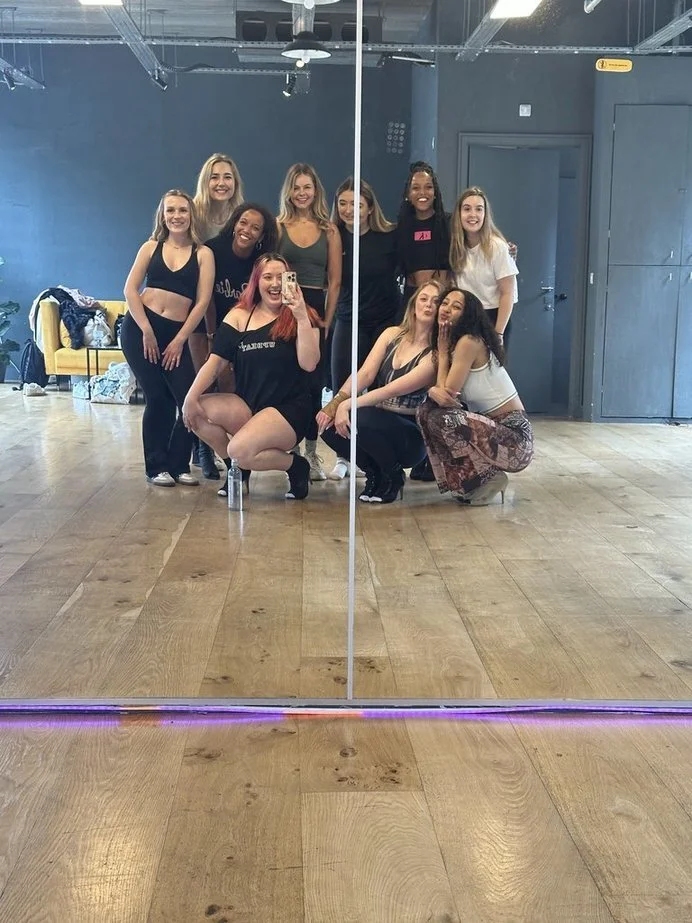 A group of ten women taking a mirror selfie in a dance studio after a dance class in Nottingham