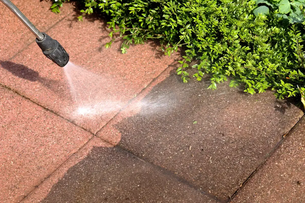 Nettoyage de dalles de terrasse colorées montrant le retrait de la pollution noire par Rince Caillou.