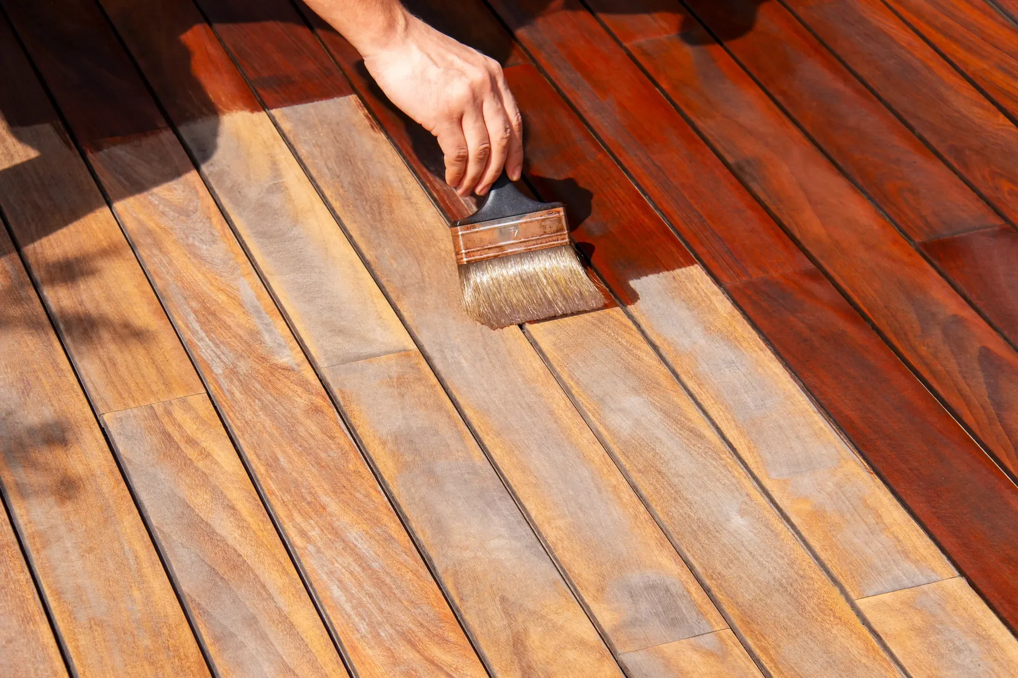 Pose manuelle du saturateur au pinceau sur une terrasse en bois pour une protection durable.