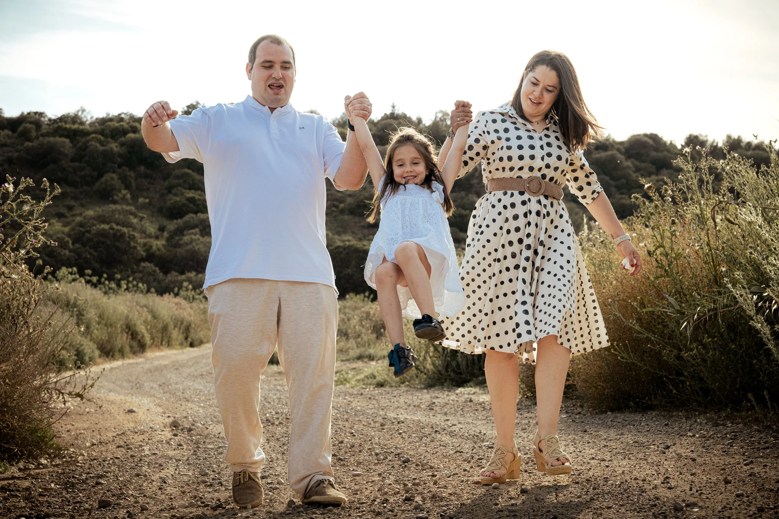 Una familia de tres personas, con un niño pequeño, caminando por un sendero en el campo y disfrutando del momento juntos.