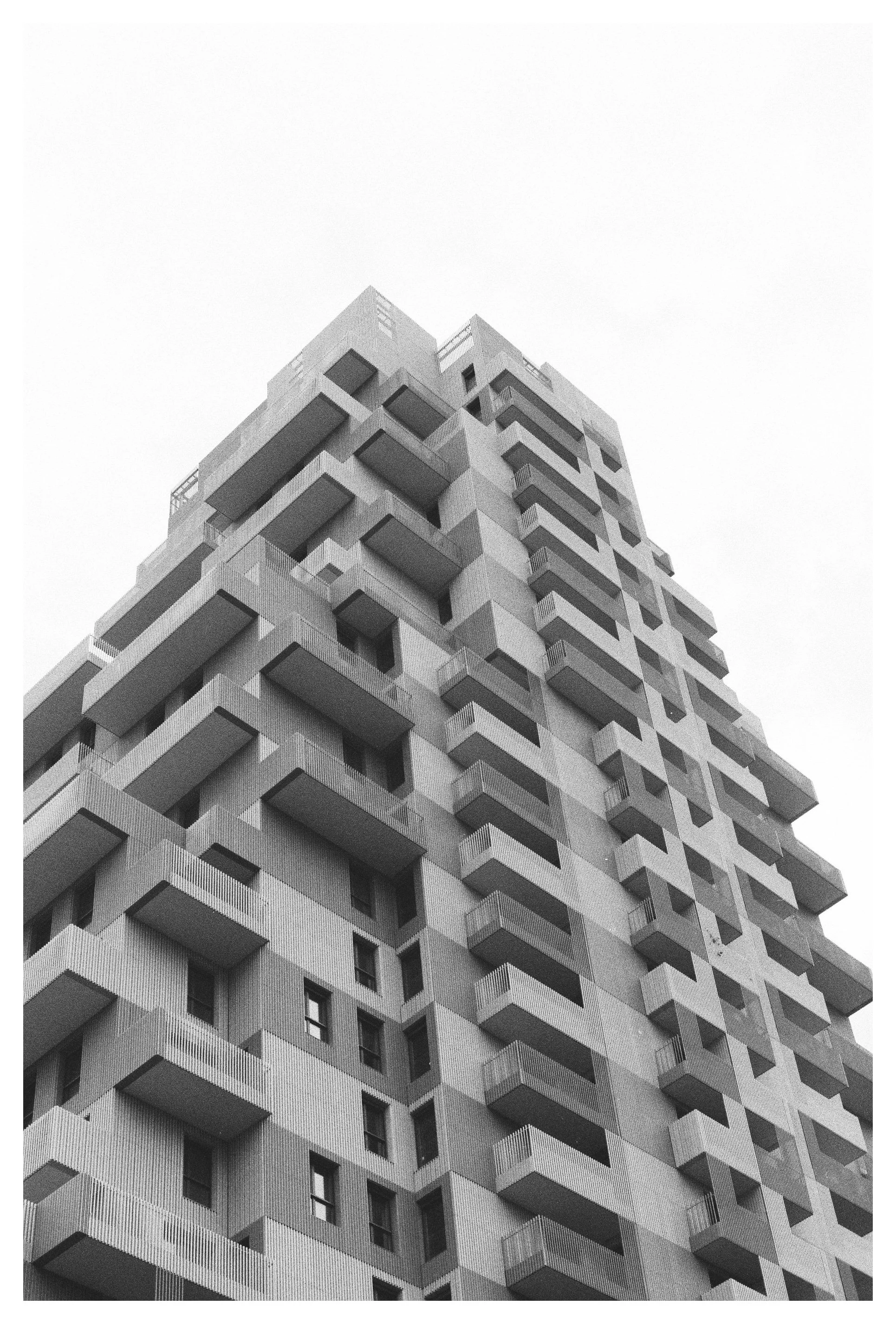 Edificio de apartamentos moderno y alto con balcones en varias alturas, vista desde abajo, en blanco y negro
