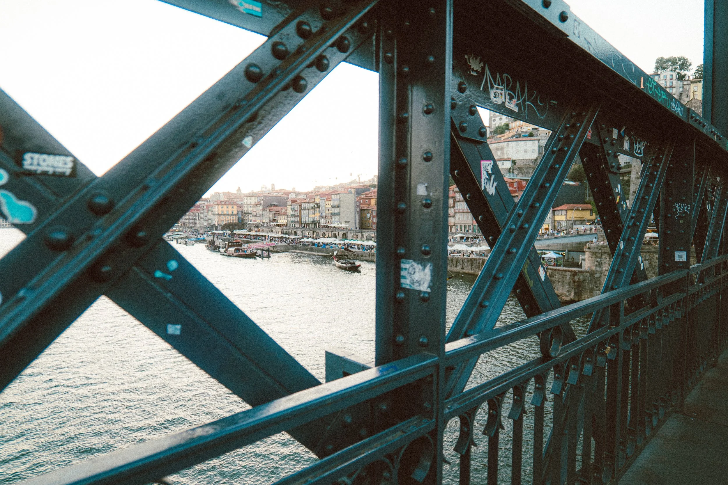 Vista de una ciudad al lado del río, vista a través de una estructura de hierro de un puente