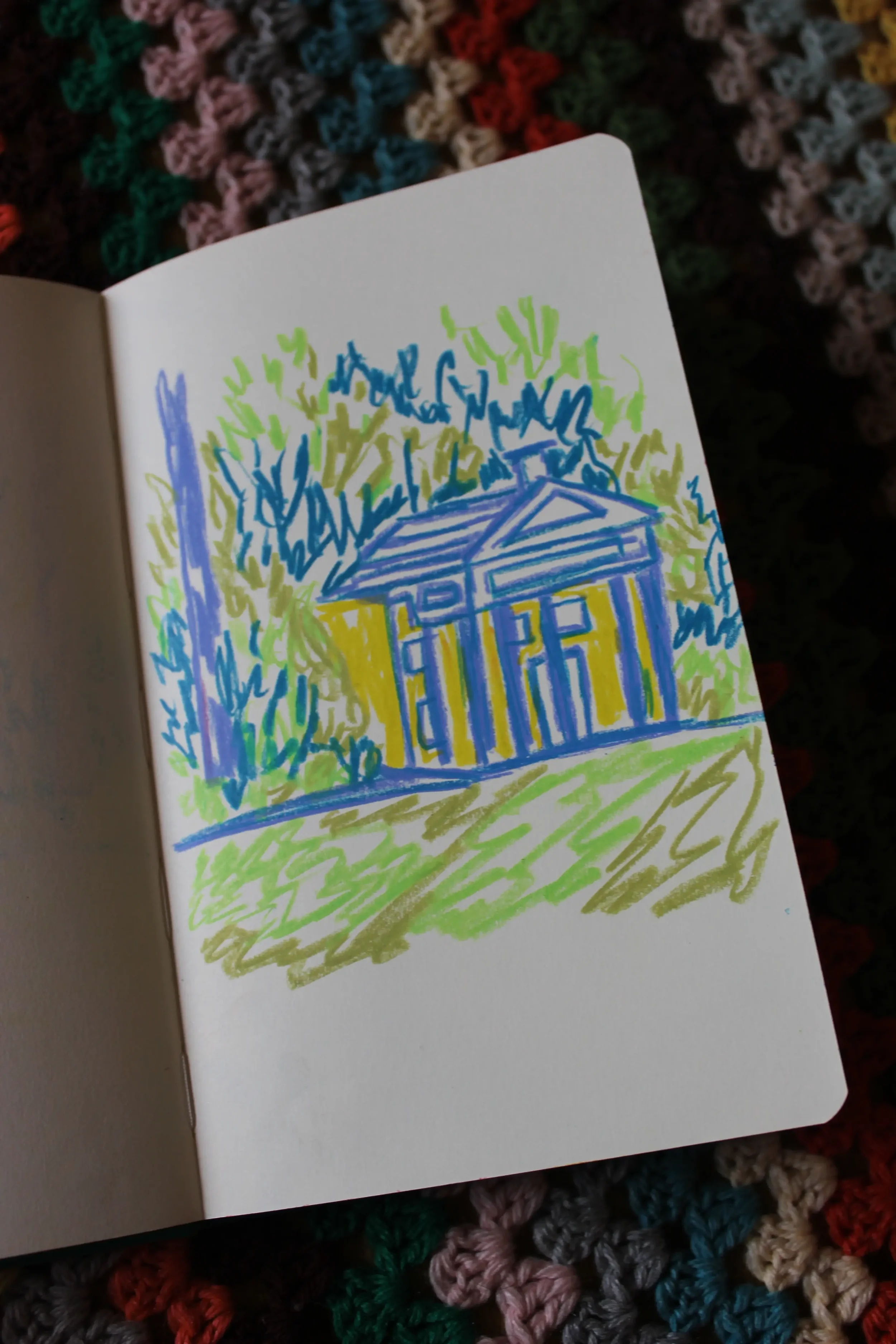 A colorful drawing of a house with a front porch, surrounded by trees and grass, created with blue, yellow, green, and purple markers on paper.