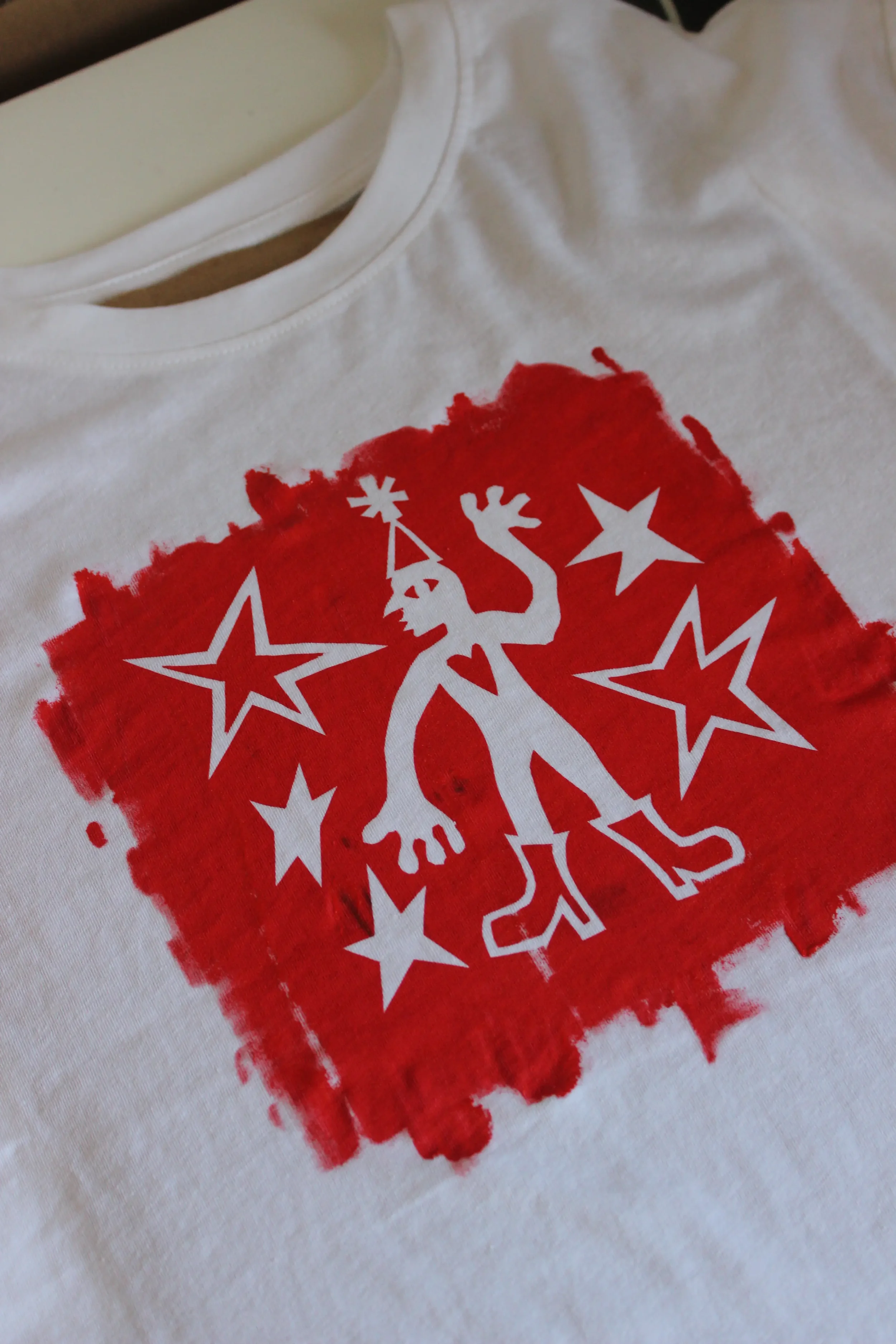 A white T-shirt with a red and white graphic design featuring stars, and a stylized goblin figure.