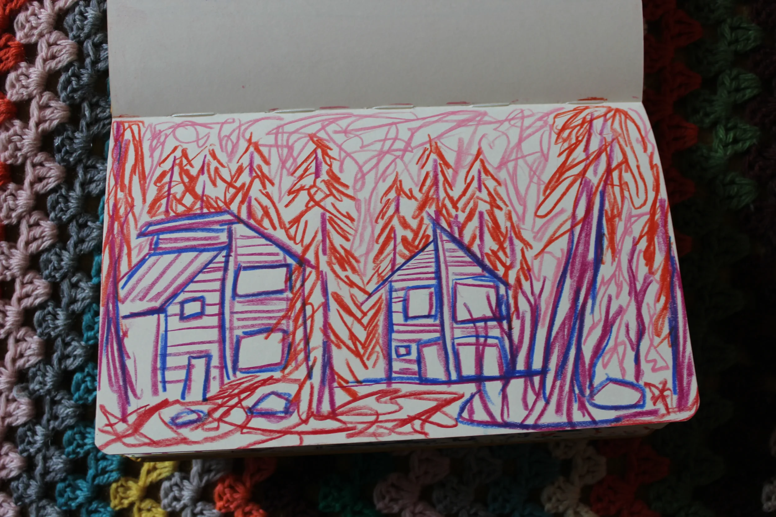 Drawing of houses and trees with orange and red scribbles, and blue outlines on white paper.