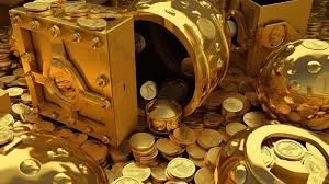 A collection of gold-colored coins spilling out of a decorative box with ornate details, some coins outside the box on a flat surface.