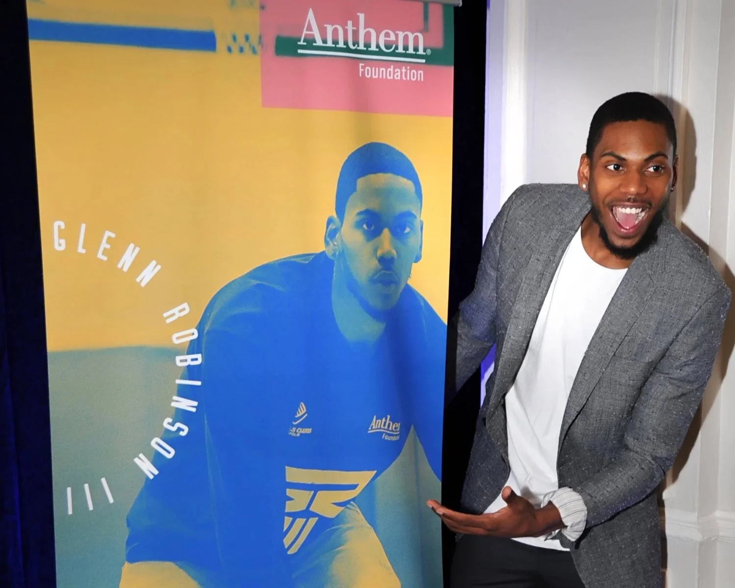 A happy man pointing to a poster of Glenn Robinson at an Anthem Foundation event.