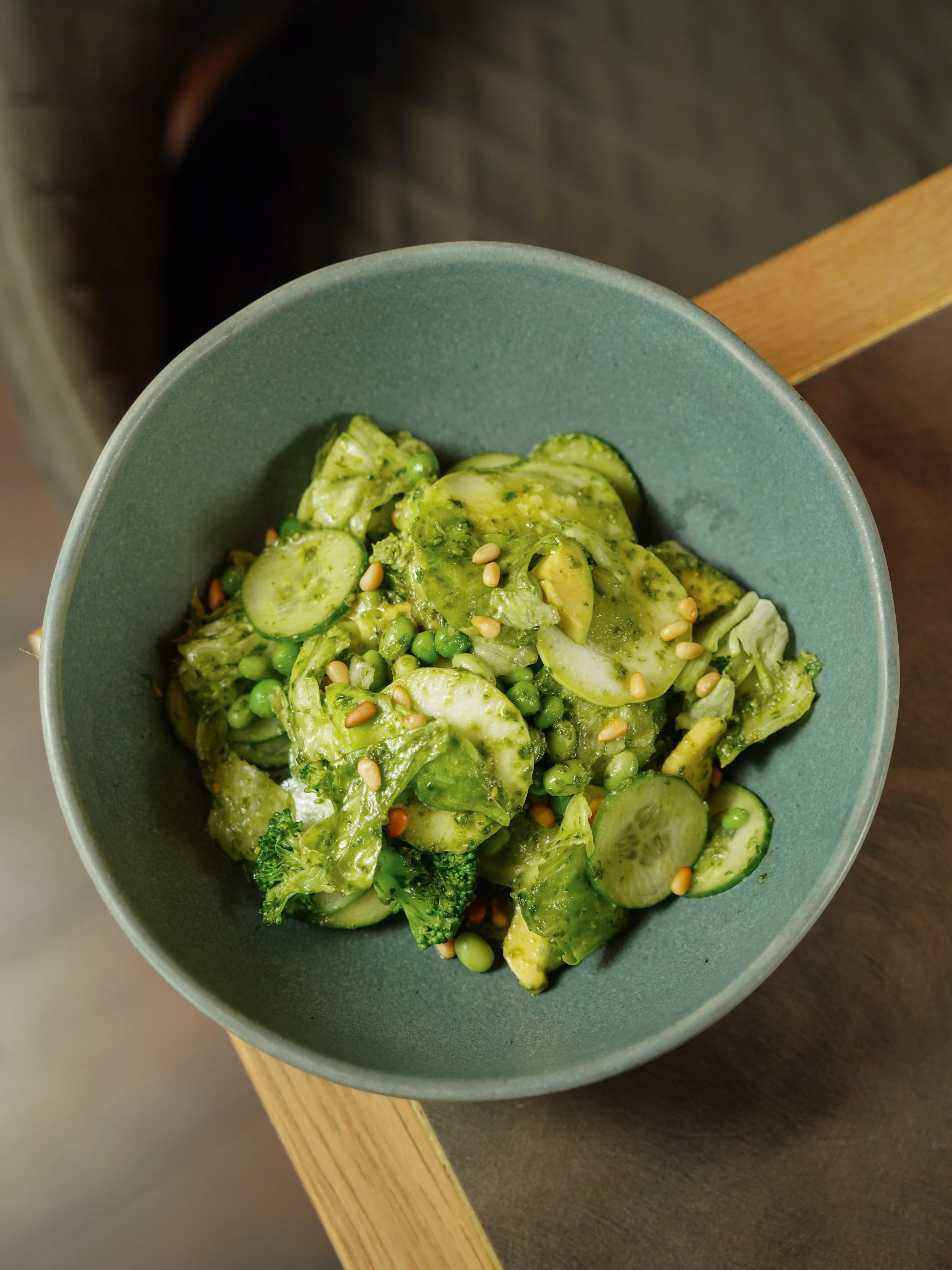 A bowl of cucumber and green vegetable salad topped with pine nuts.
