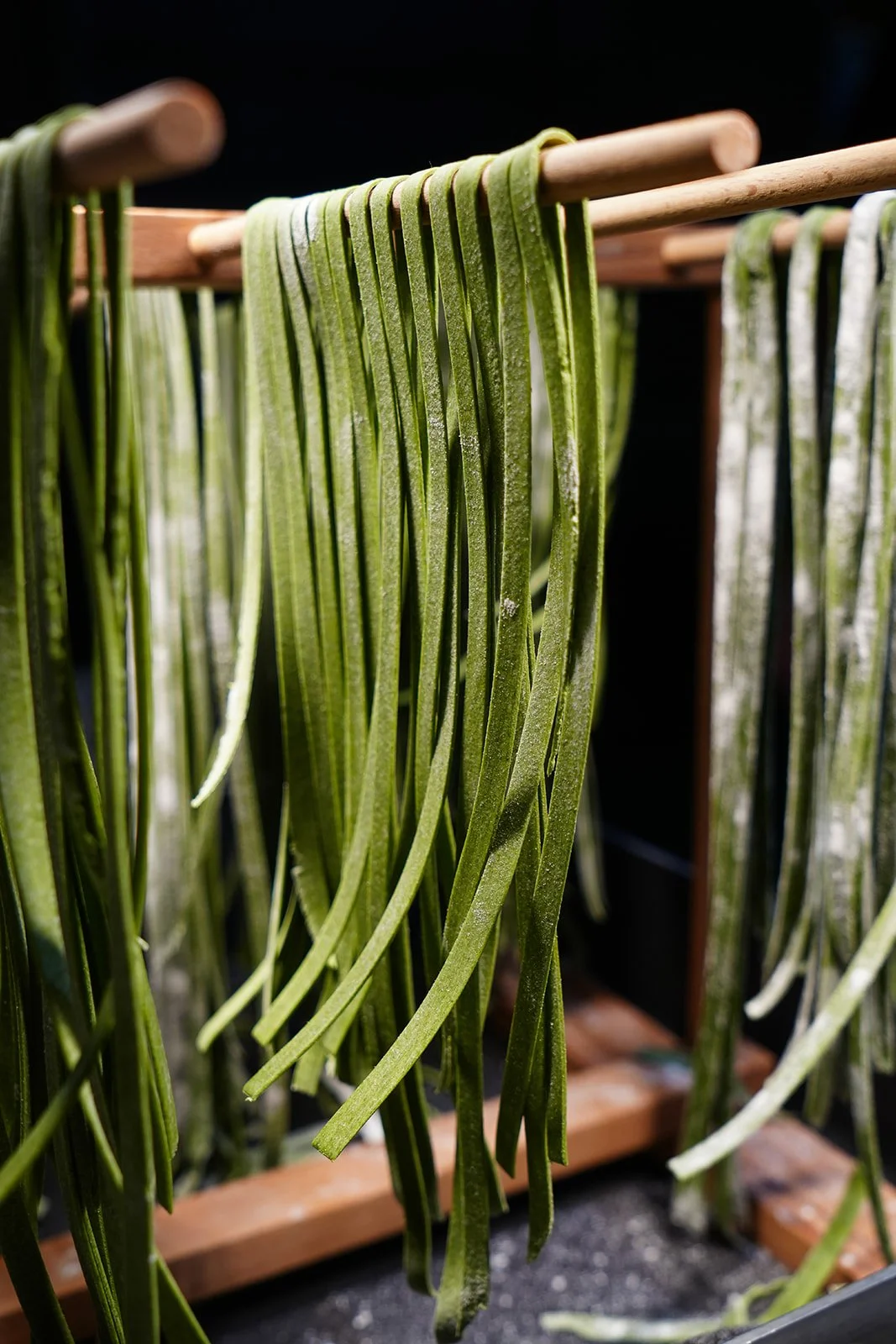 Lacets verts suspendus sur un séchoir en bois, séchant à l'air libre.